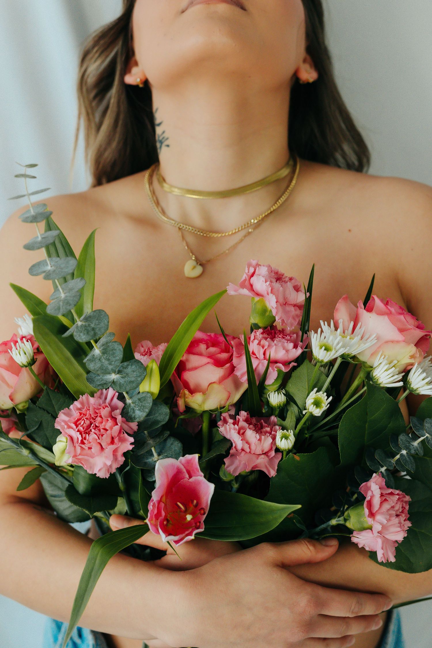 Elegant close-up of pink roses and eucalyptus bouquet with gold necklace accessories.