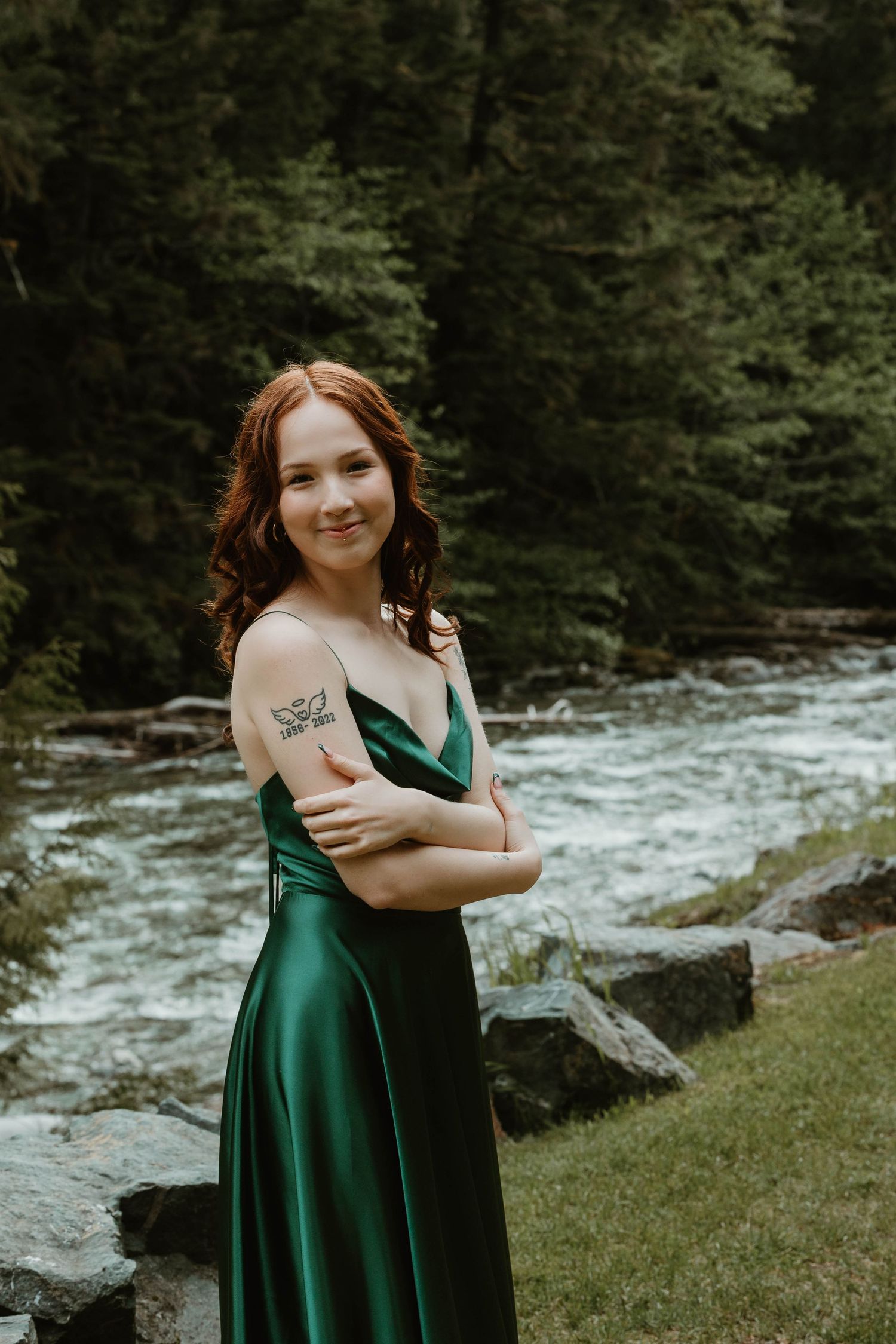 Natural outdoor portrait by flowing river wearing emerald formal dress.