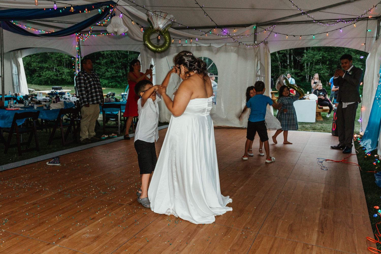First dance at a wedding reception under a tent with white decor and string lights.