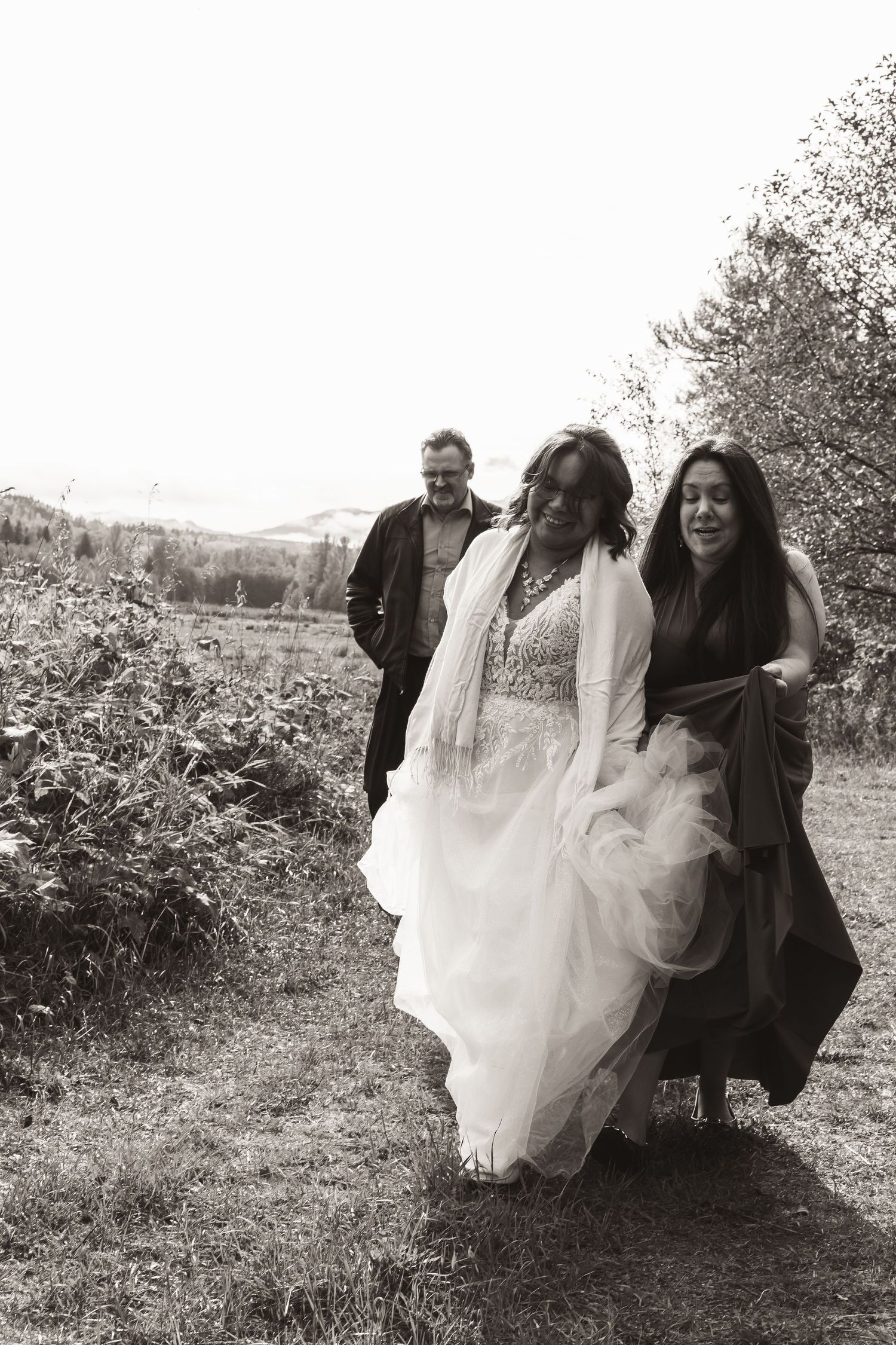 Black and white photo of a bride and companions walking along a scenic path.