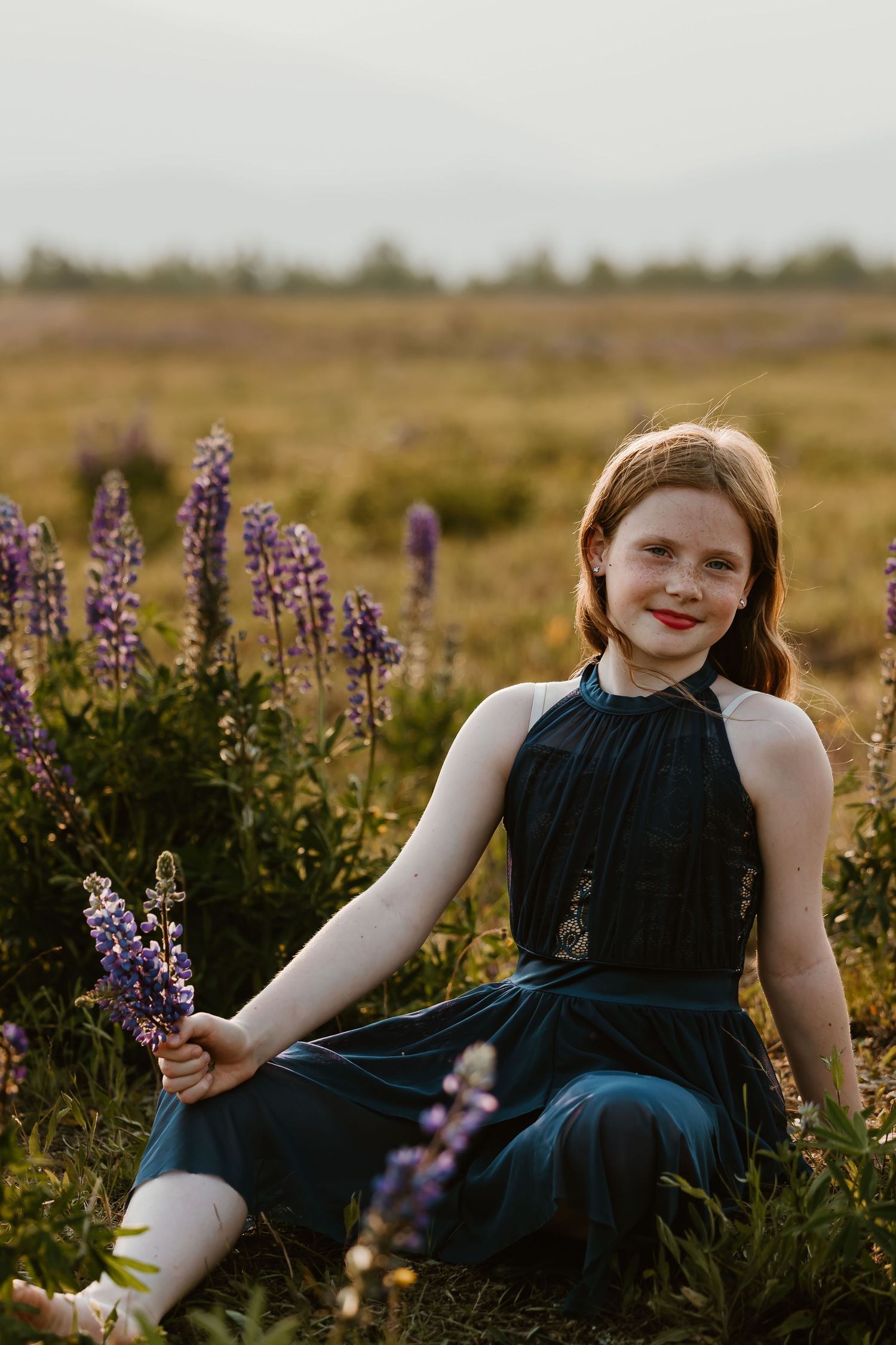 A dreamy sunset photoshoot in a field of purple wildflowers with a navy dress.