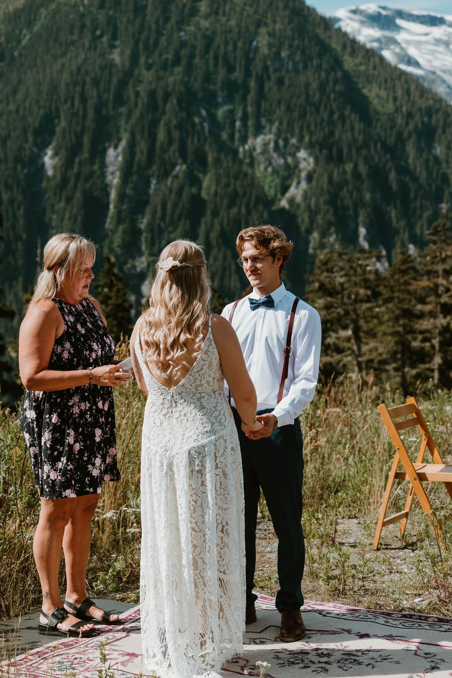 An intimate mountain wedding ceremony with a small group gathered on a scenic overlook.