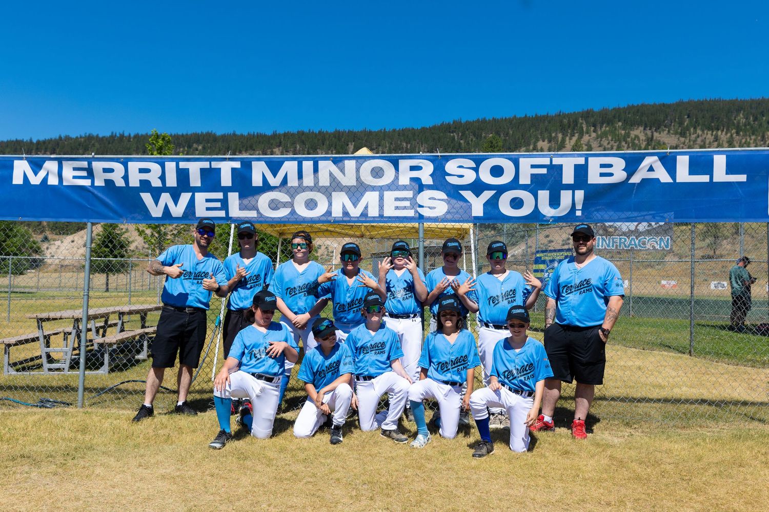 Youth softball team posing for group photo under welcome banner.