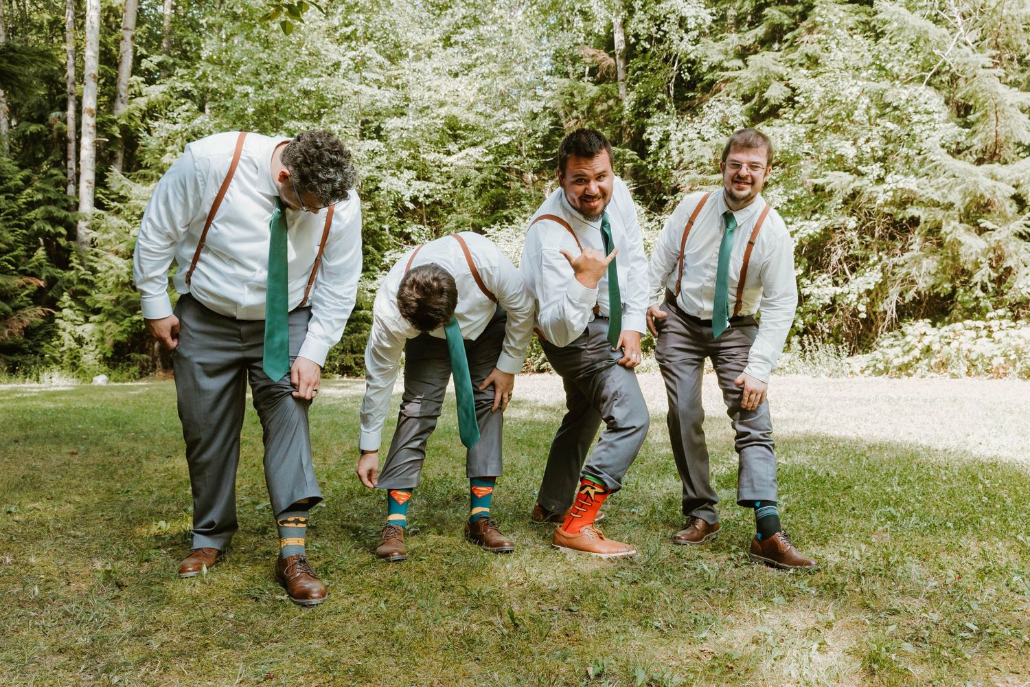 Groomsmen in suspenders and dress shirts checking their colorful socks in a playful pose.