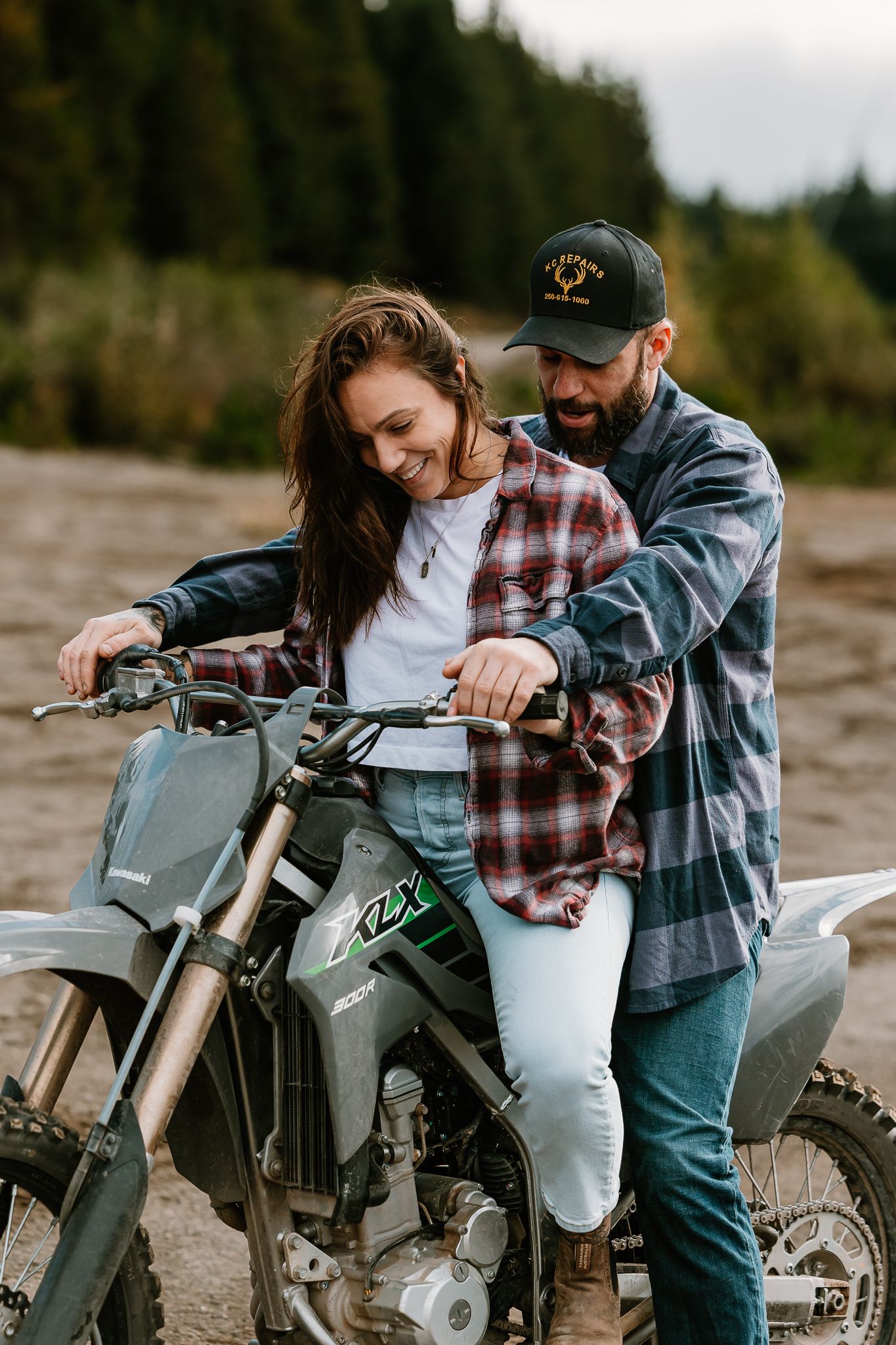 A couple sits together on a dirt bike in a romantic outdoor photoshoot series.