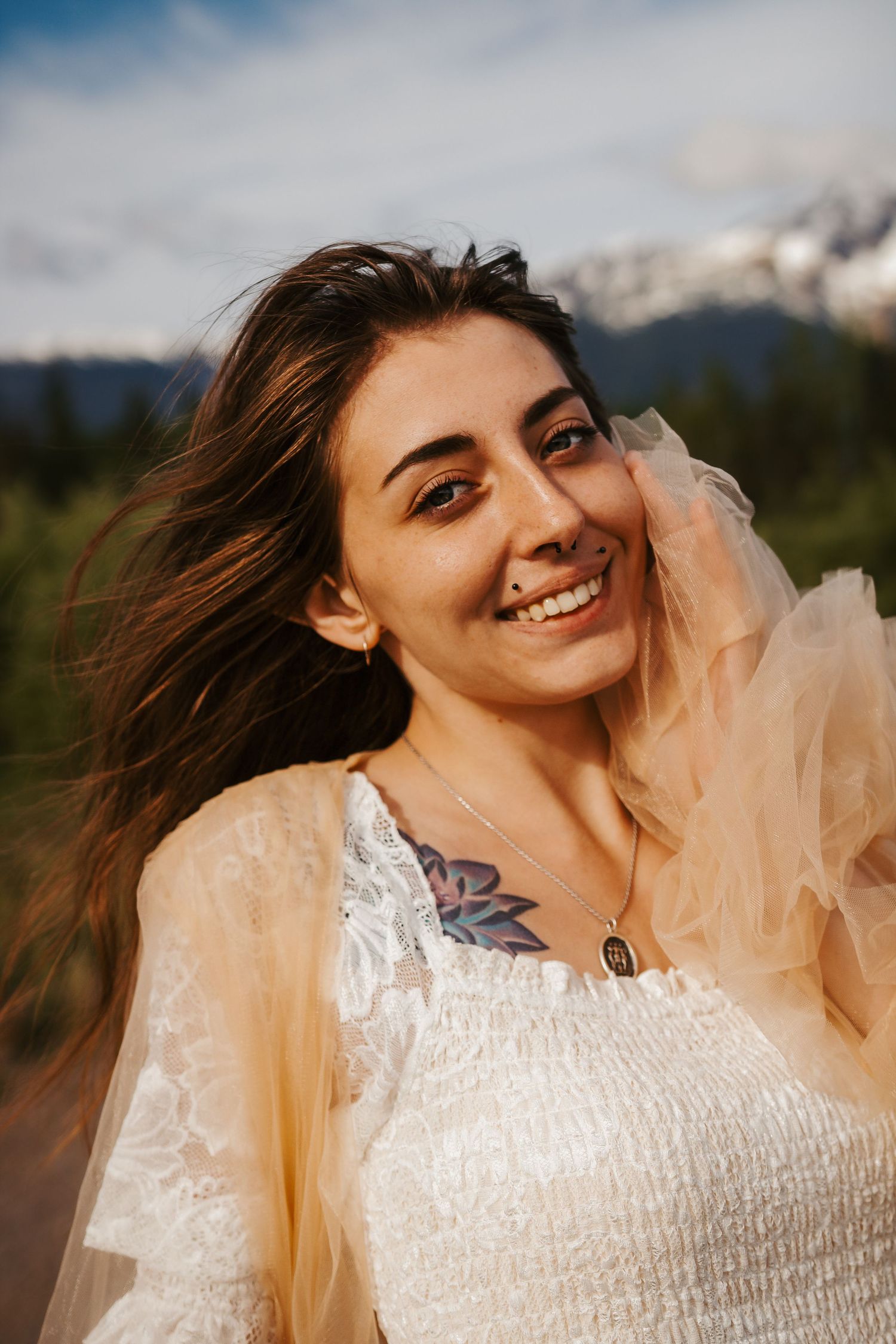 Golden hour portrait in white lace dress with mountains in background.