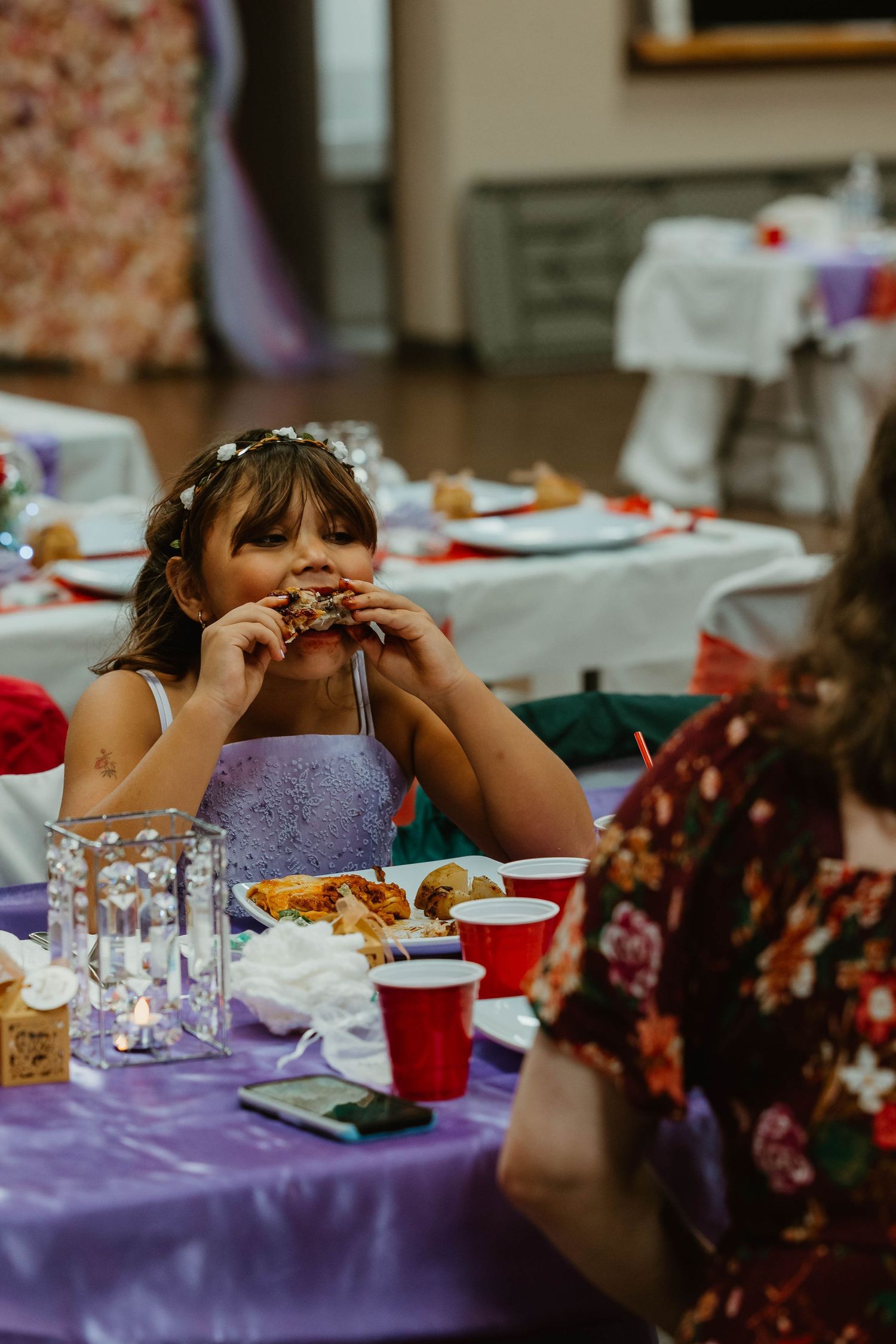 A guest enjoying food at a reception table with purple tablecloths and red decorative accents.