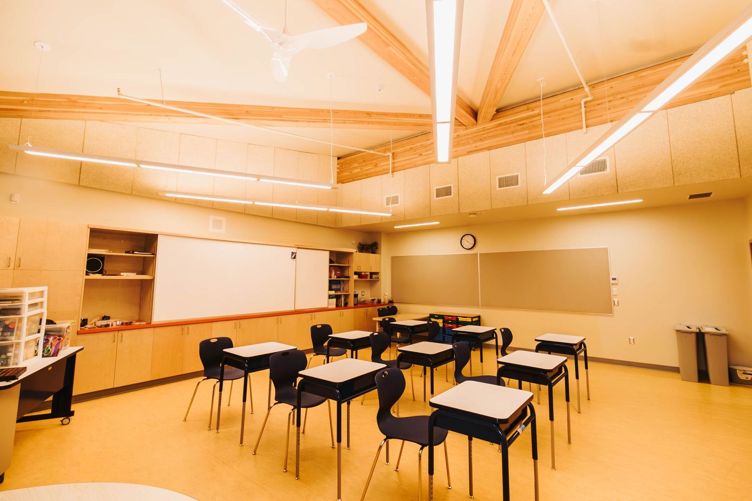 Classroom with black chairs and desks arranged in rows under fluorescent lighting.