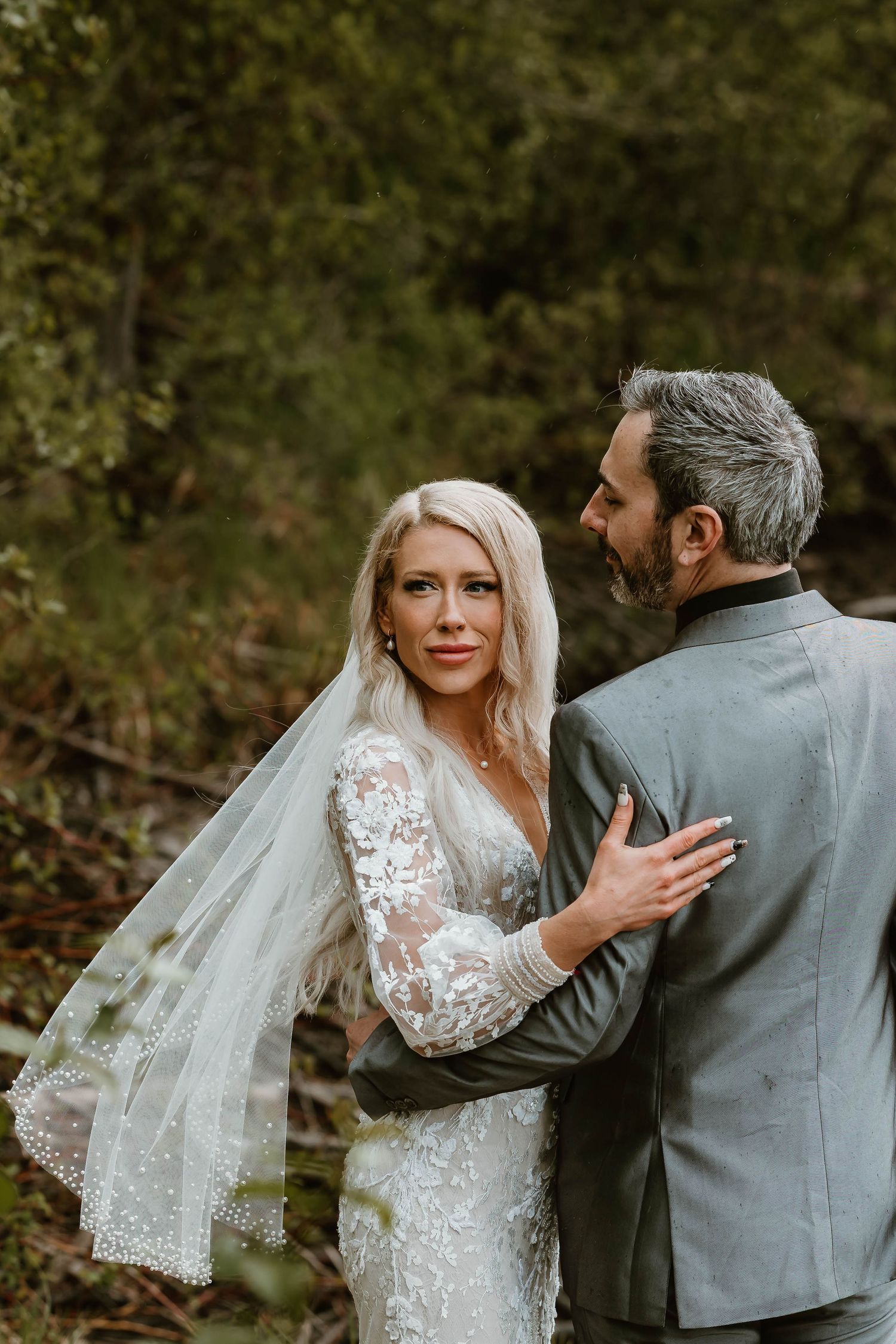 A romantic wedding sequence showing a couple in a forest setting with the bride in lace and groom in grey suit.