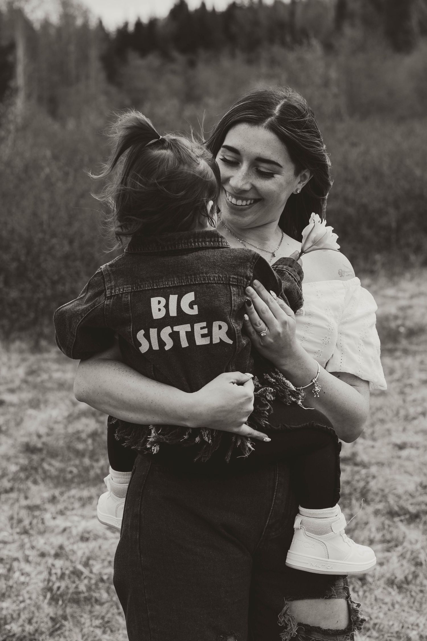 A heartwarming embrace captured in black and white, featuring a denim jacket with 'Big Sister' text.