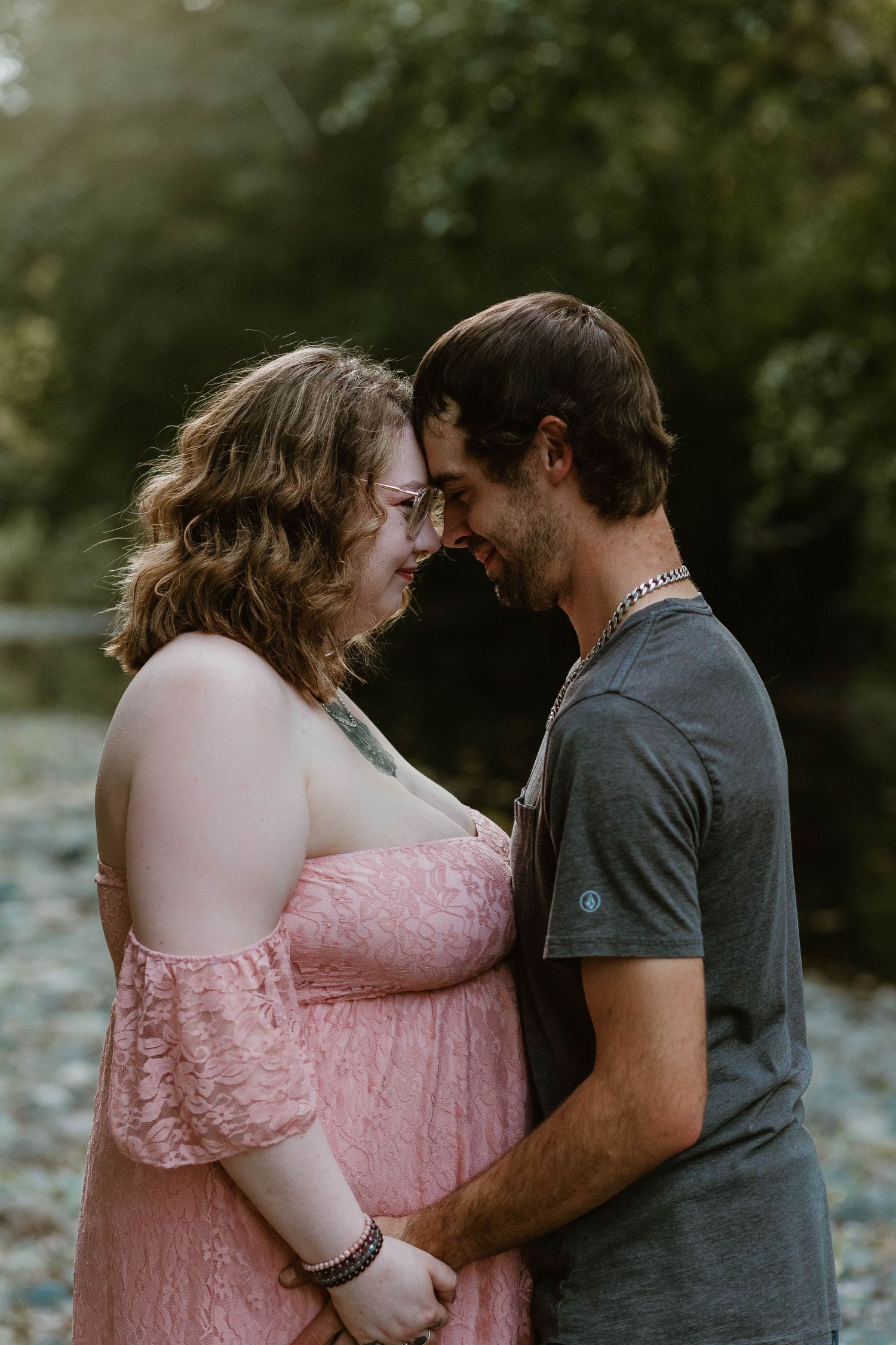 A couple shares a tender moment while standing close together outdoors.