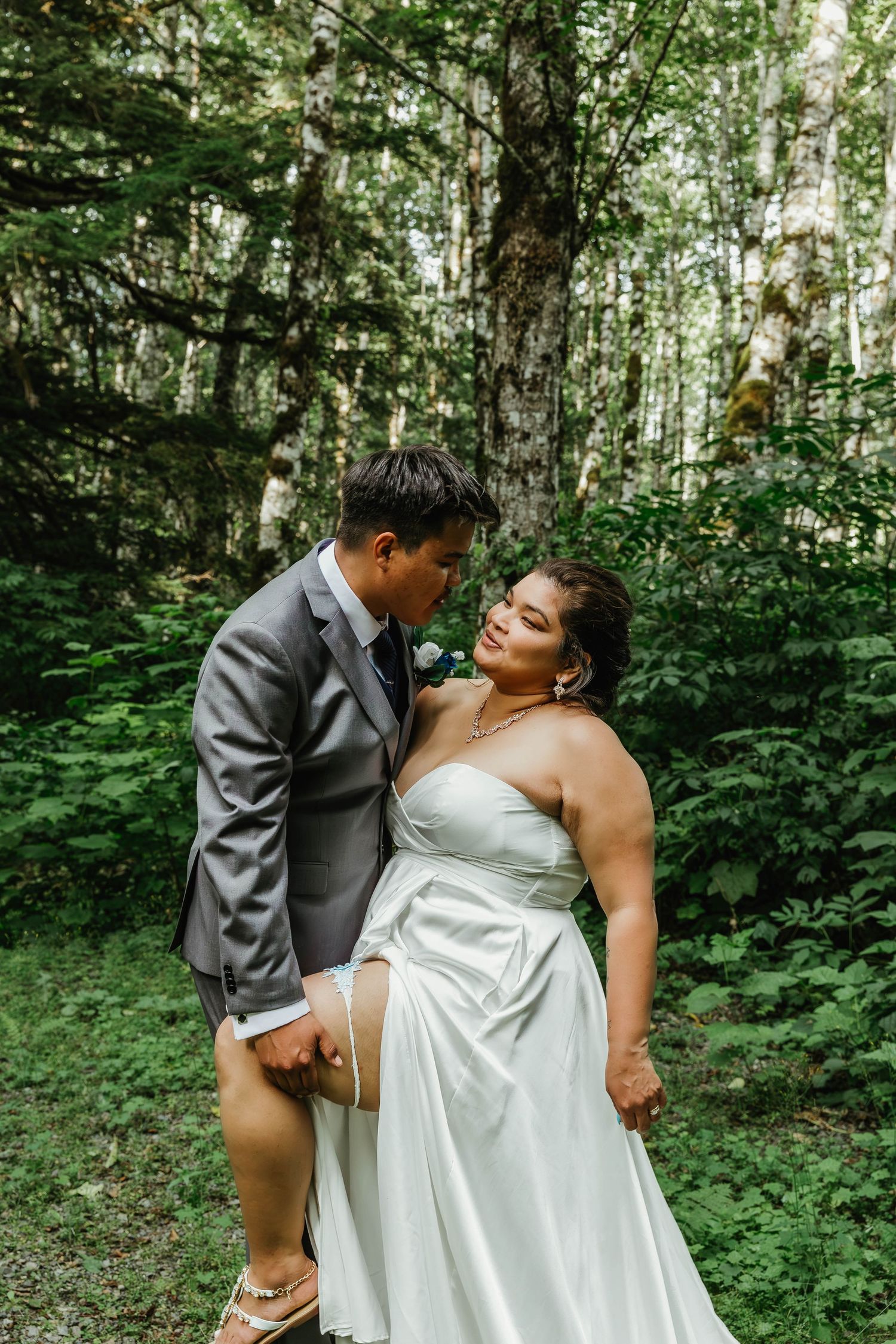 Bride and groom share an intimate moment in a lush forest setting.