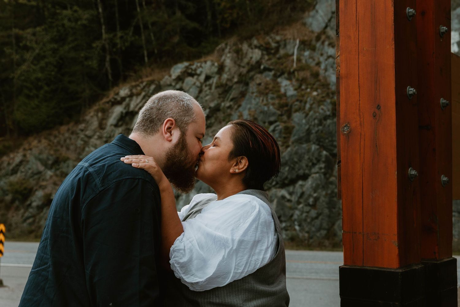 An intimate moment shared between a couple against a rocky outdoor backdrop.