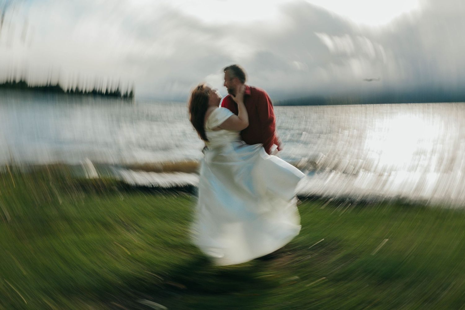 Artistic motion blur photo of a couple spinning in a romantic moment by a lake.