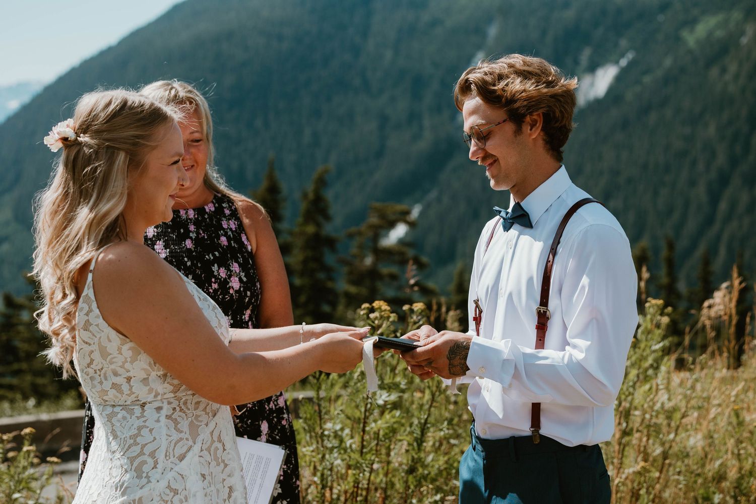 A joyful moment during a mountain-top wedding ceremony with evergreen forests in the background.