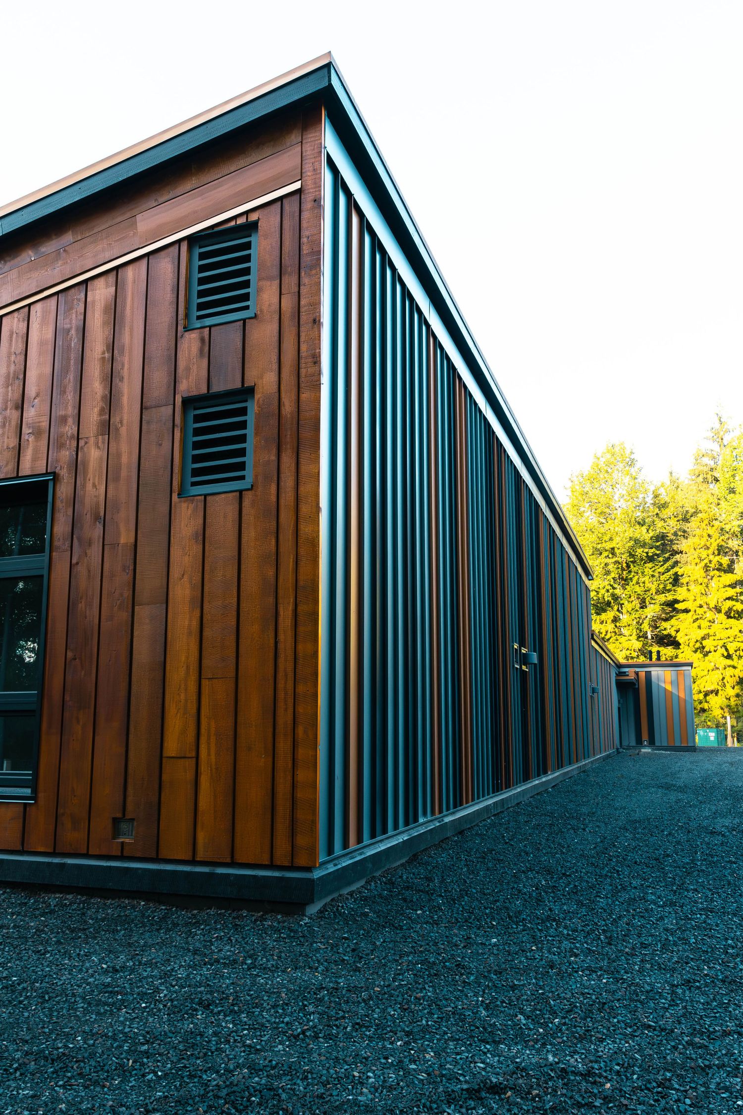 Angular modern building exterior featuring wood paneling and blue vertical accents.