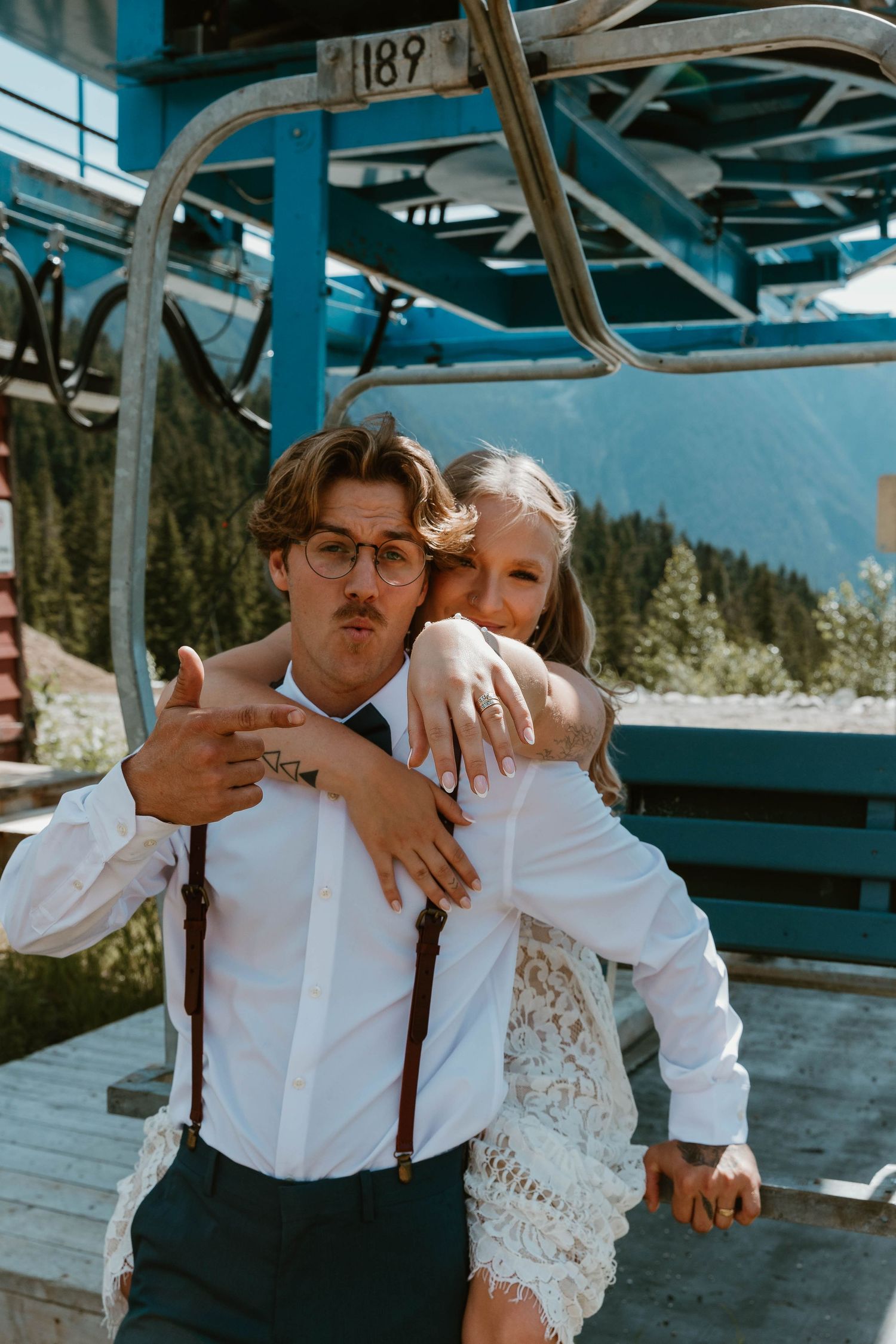 A sweet embrace on a chairlift with mountains in the background.