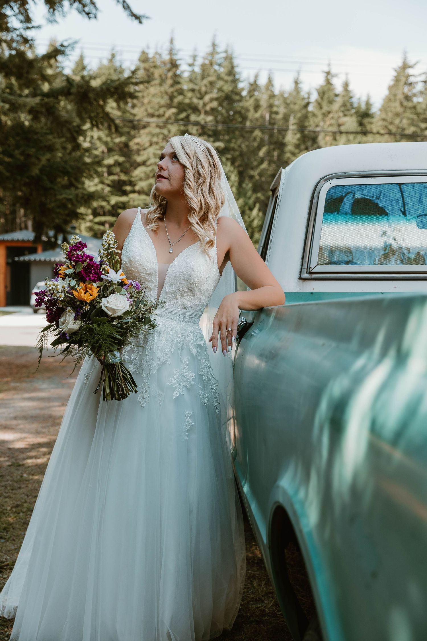Beautiful wedding dress against vintage turquoise truck with colorful bouquet.