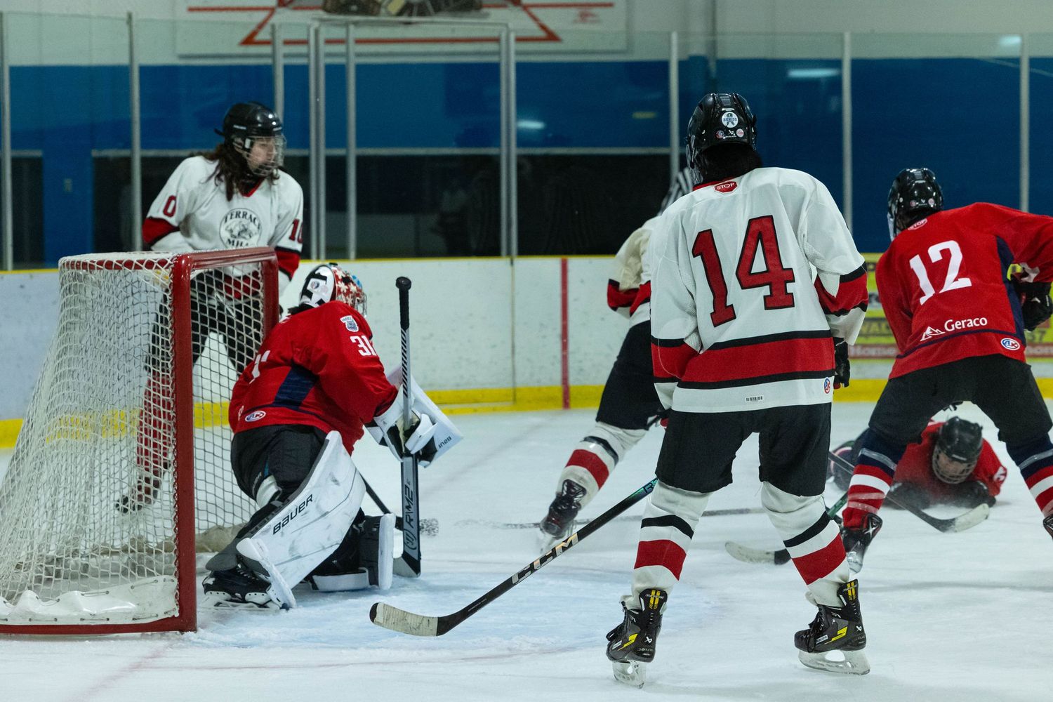 Hockey action near the goal net as players fight for position during a game.