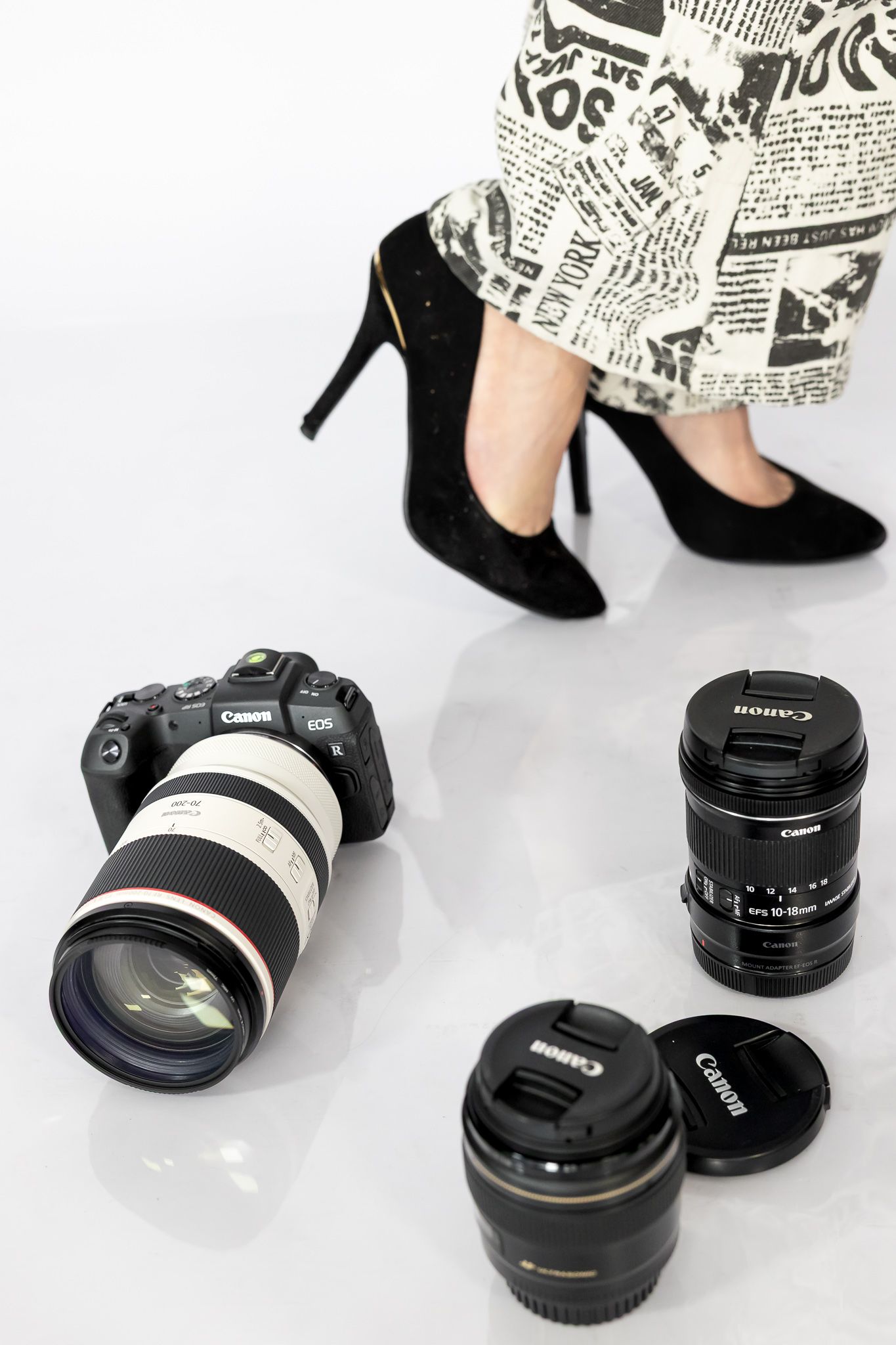 Close-up photos of black camera lenses and accessories arranged on a white background with newspaper print decor.