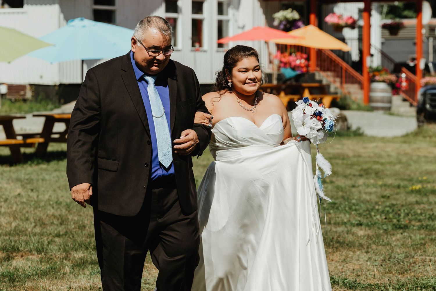 Couple walking across a sunny lawn during their outdoor wedding ceremony.