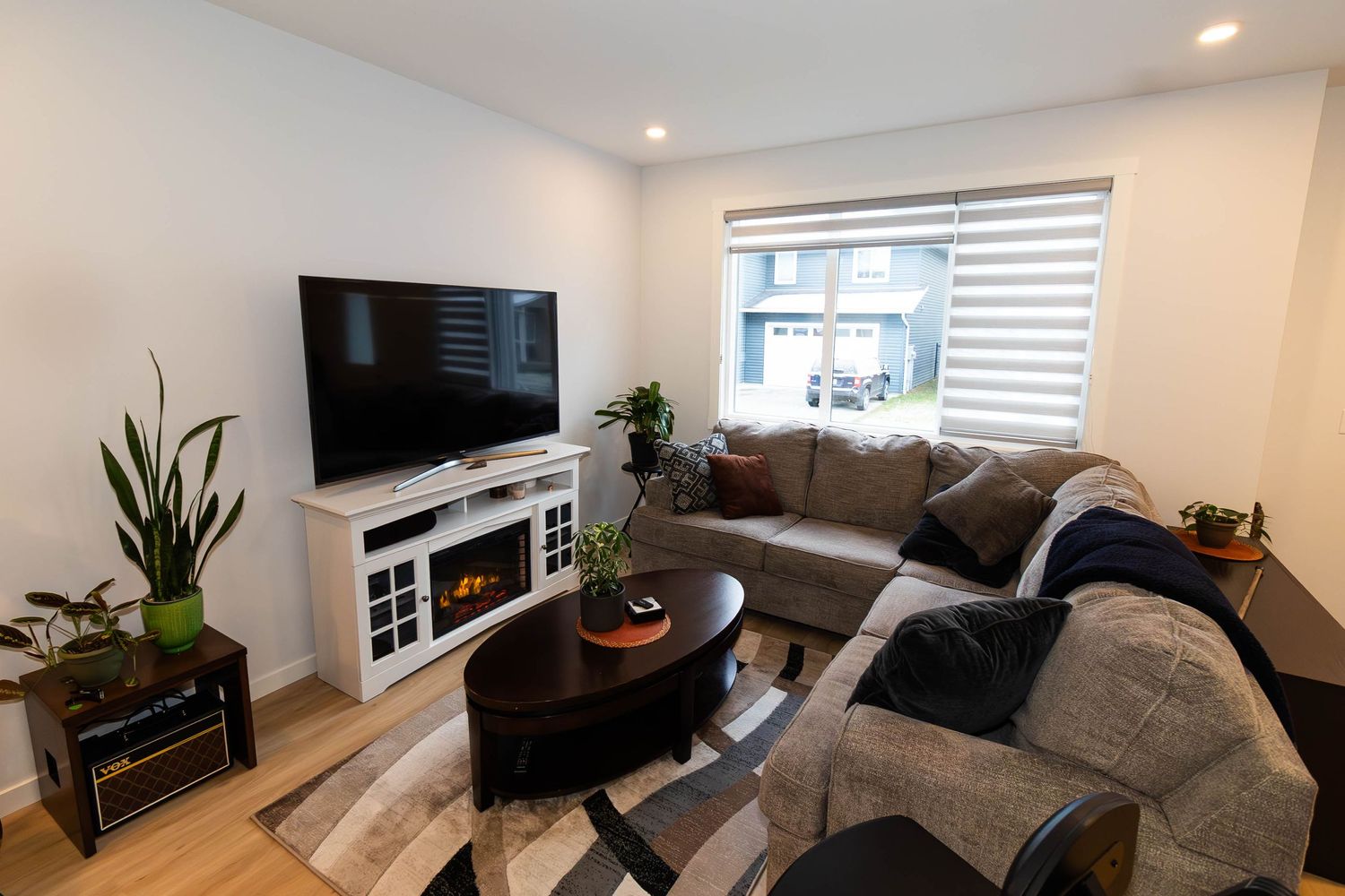 Contemporary living room with mounted TV, sectional sofa, and modern decor against white walls.