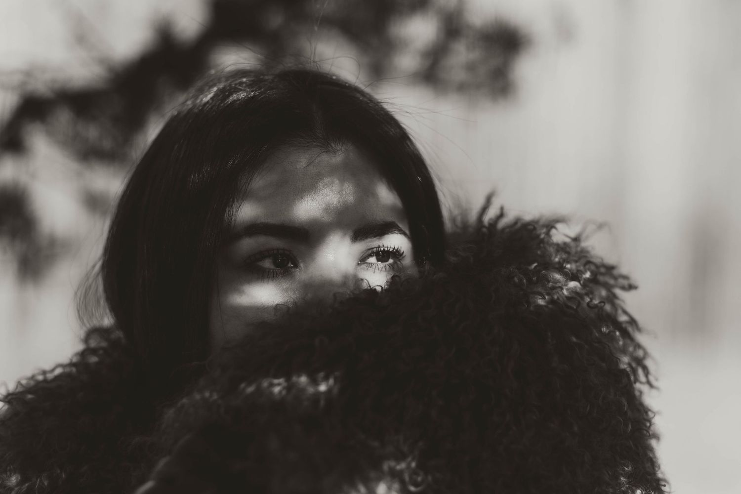 Artistic black and white portrait with shadows and fluffy fur coat texture.