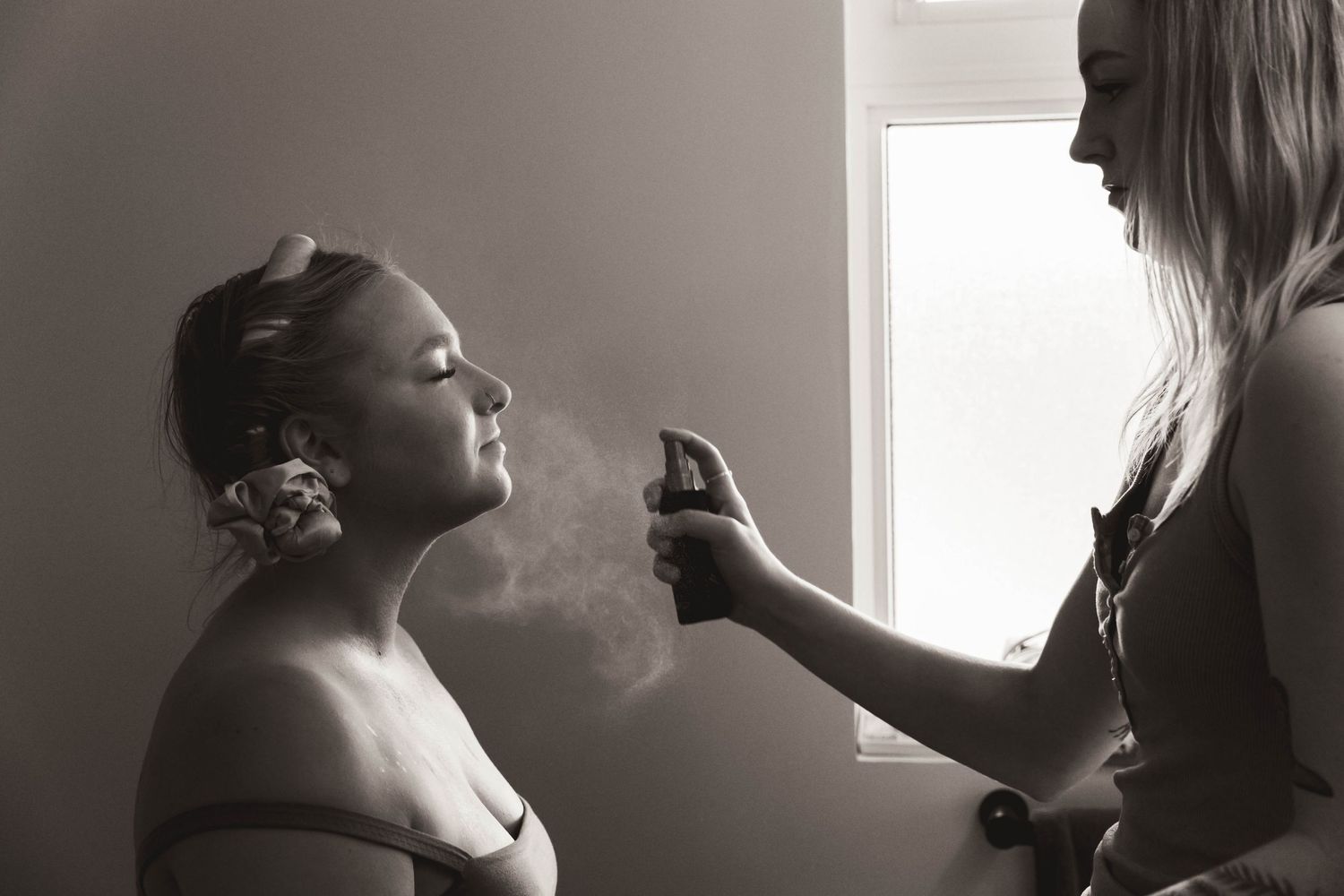 Black and white photo of wedding preparation with makeup being applied.