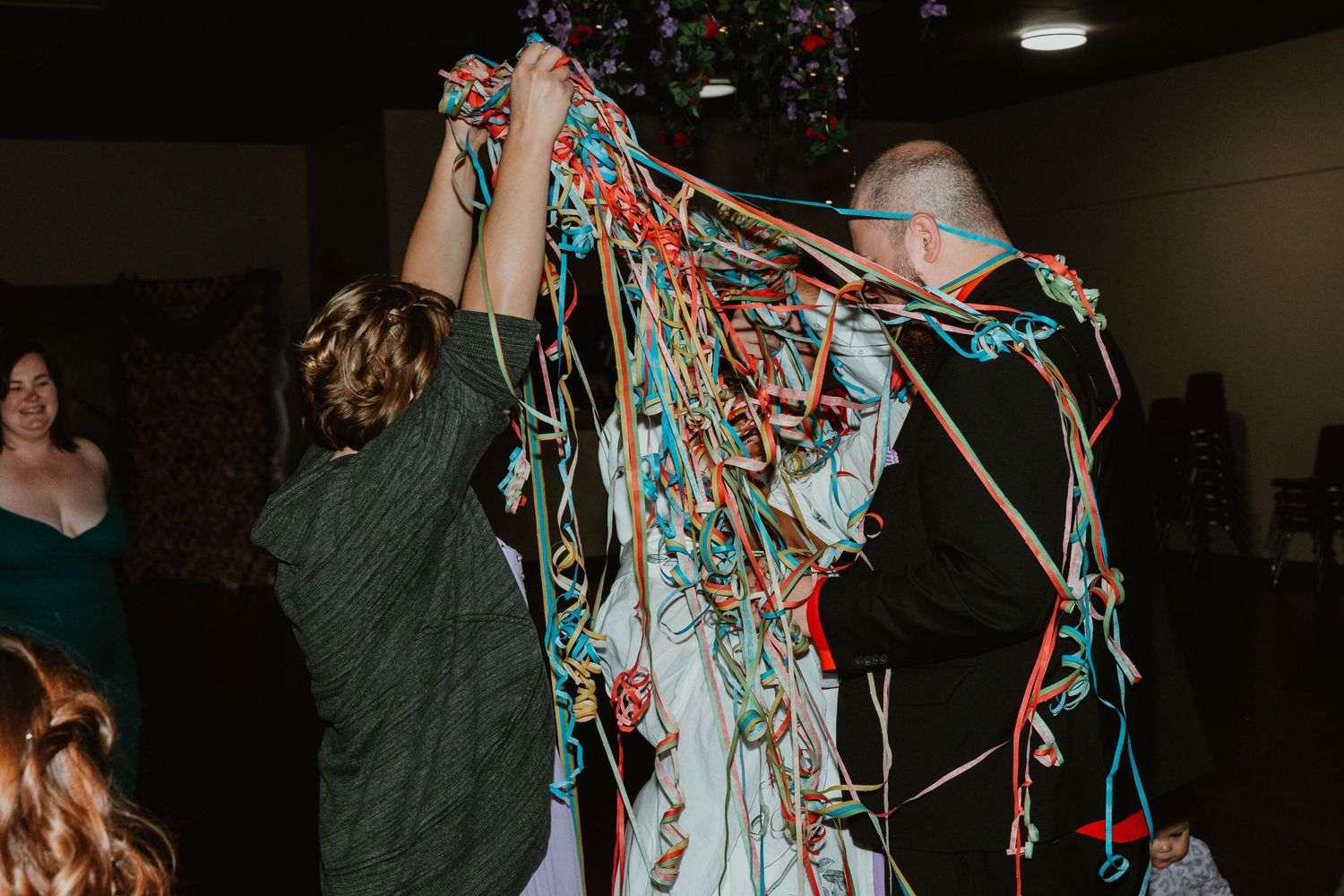 Celebrants playing with festive streamers during a party in an indoor venue.