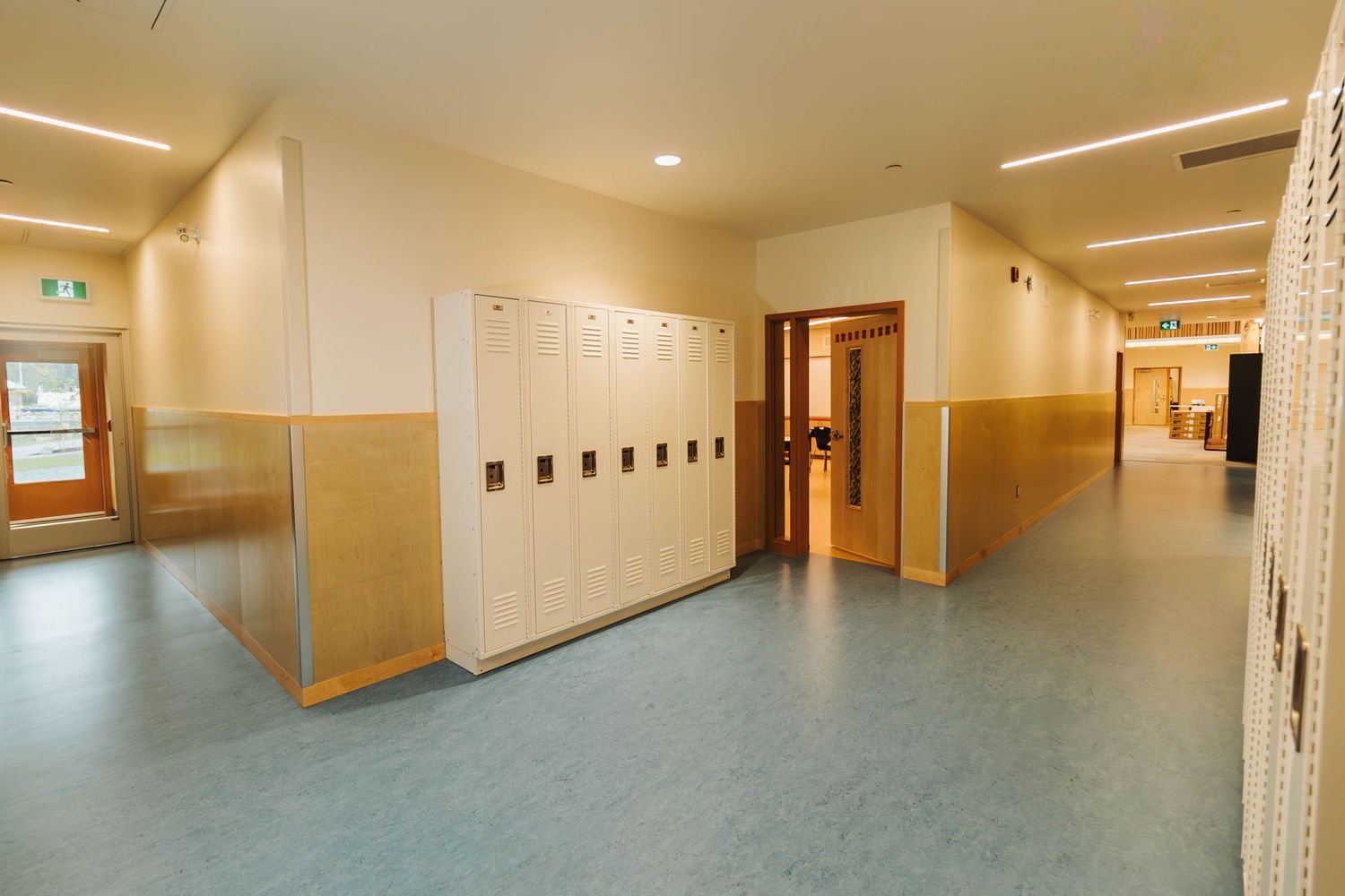 School hallway with beige walls, lockers, and fluorescent lighting shows a typical educational interior.