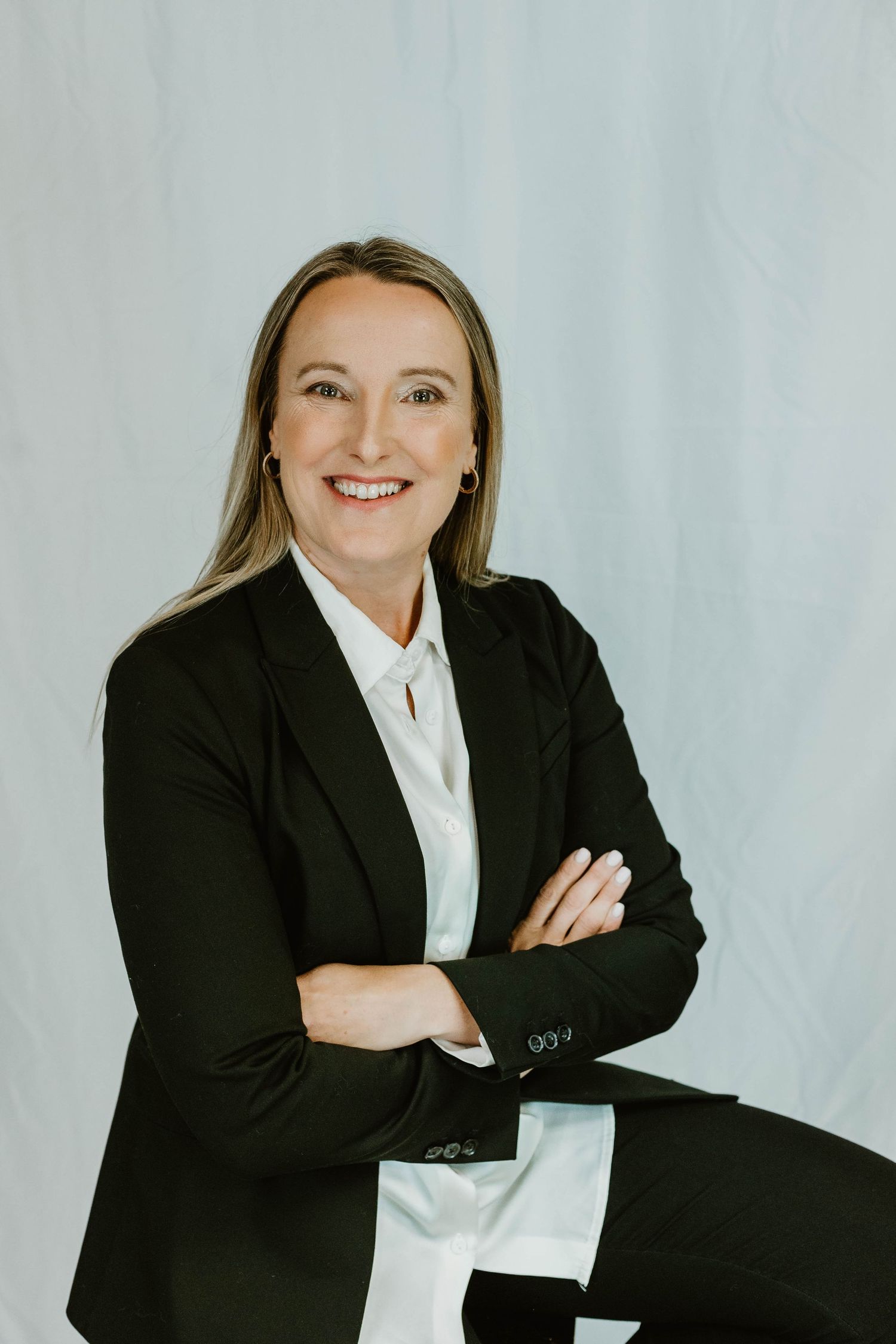 Professional headshot against light background wearing black blazer and white button-up shirt.