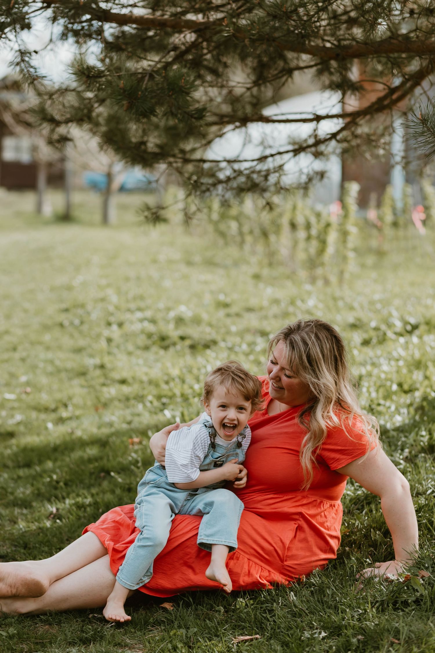 Two people sharing a tender moment while sitting together on grass in a backyard on a sunny spring day.