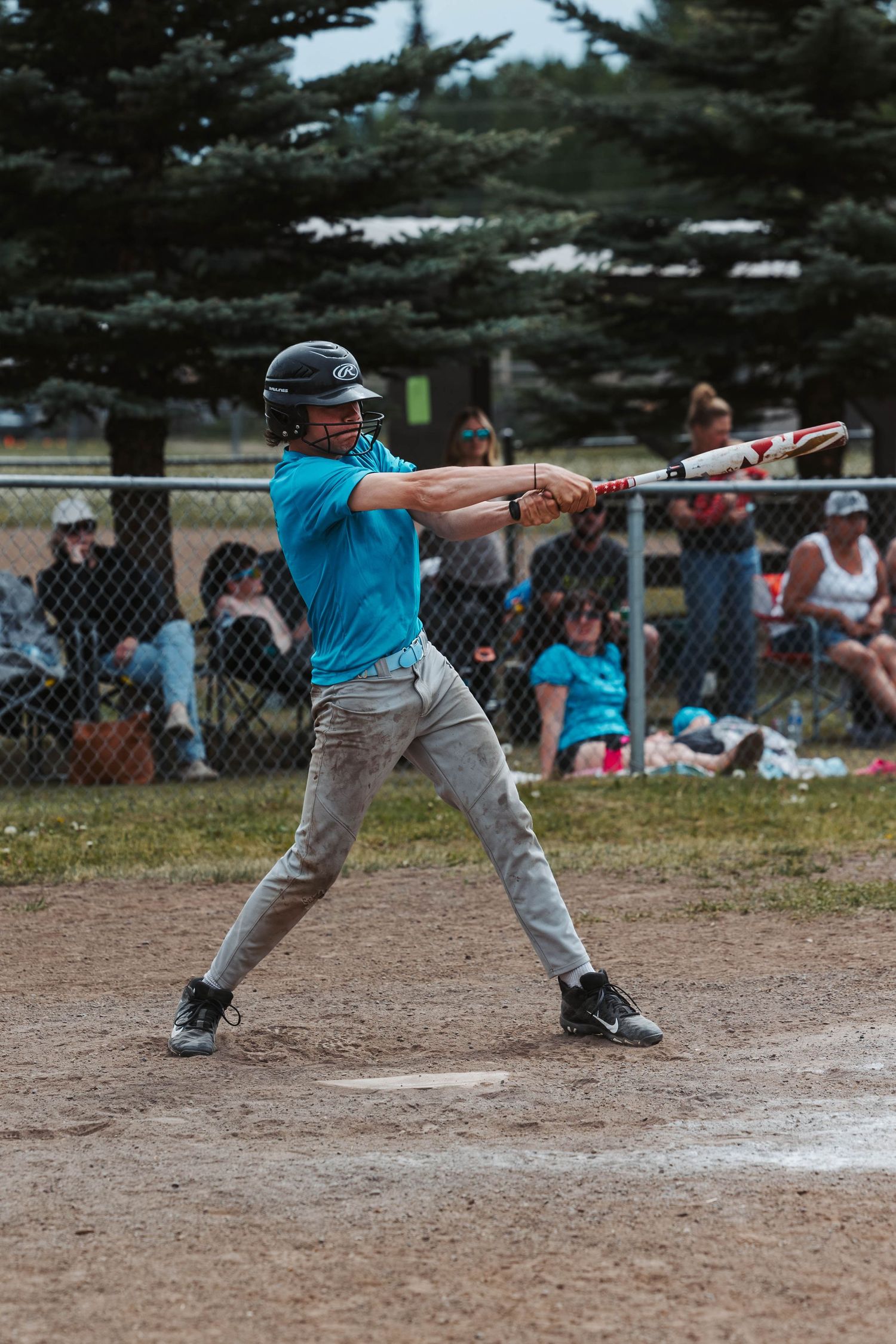 Baseball player in teal uniform shows proper batting stance during game.