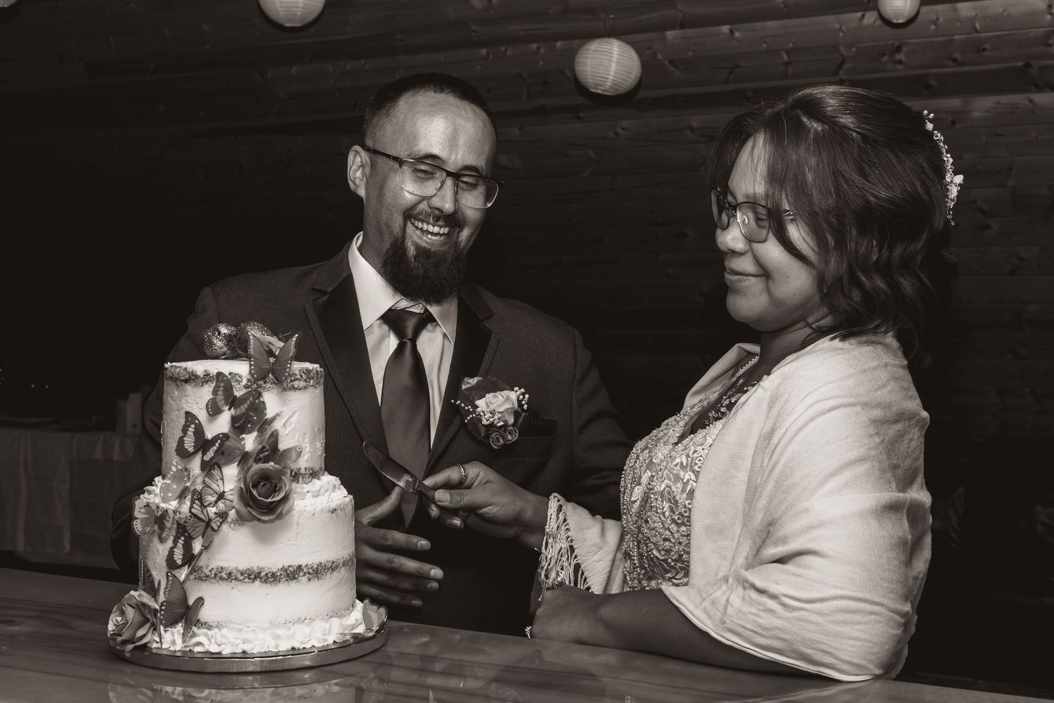 Couple shares a moment together while cutting their decorated wedding cake.