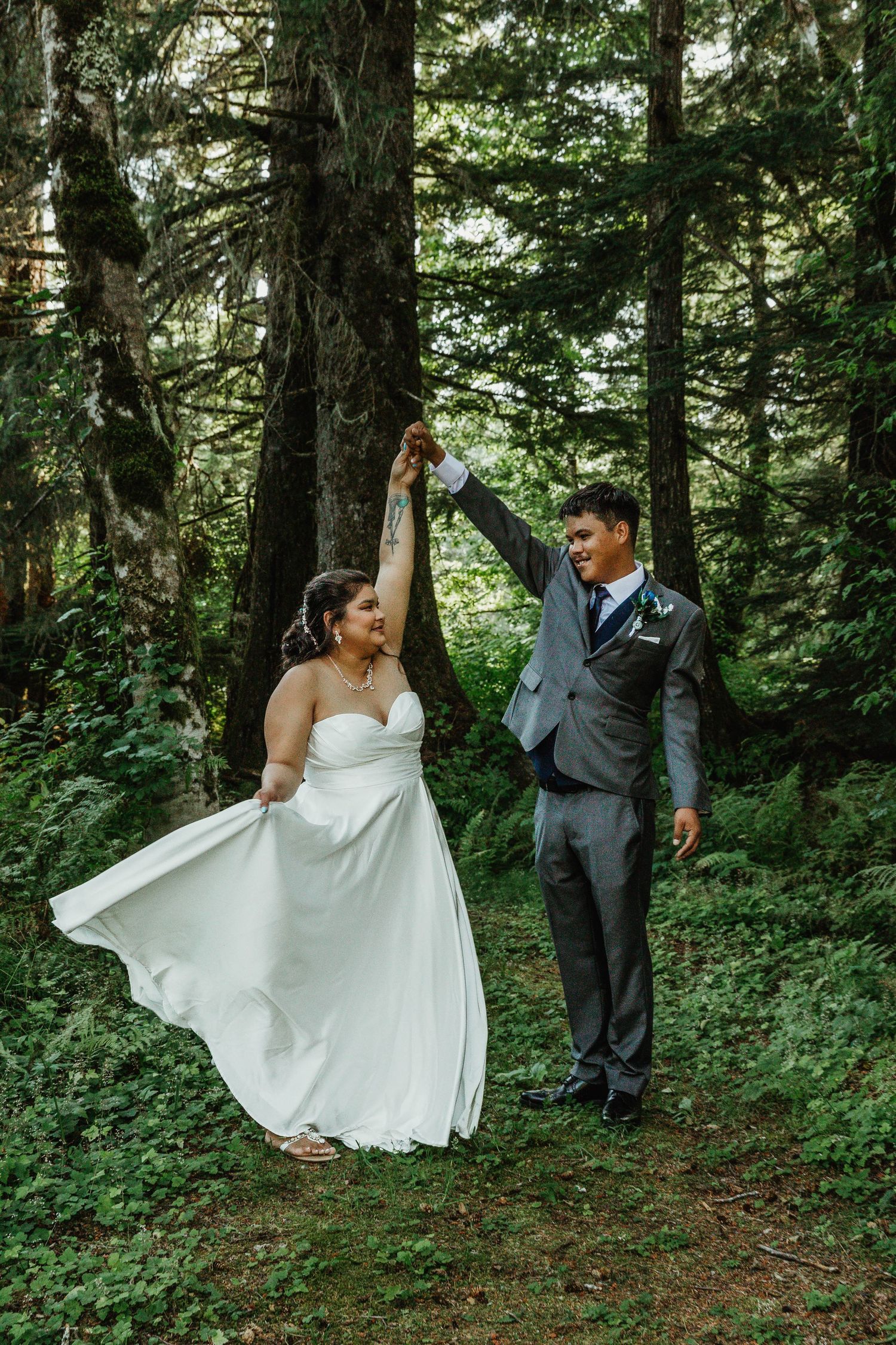 Couple dancing and twirling in a lush forest setting during their wedding.