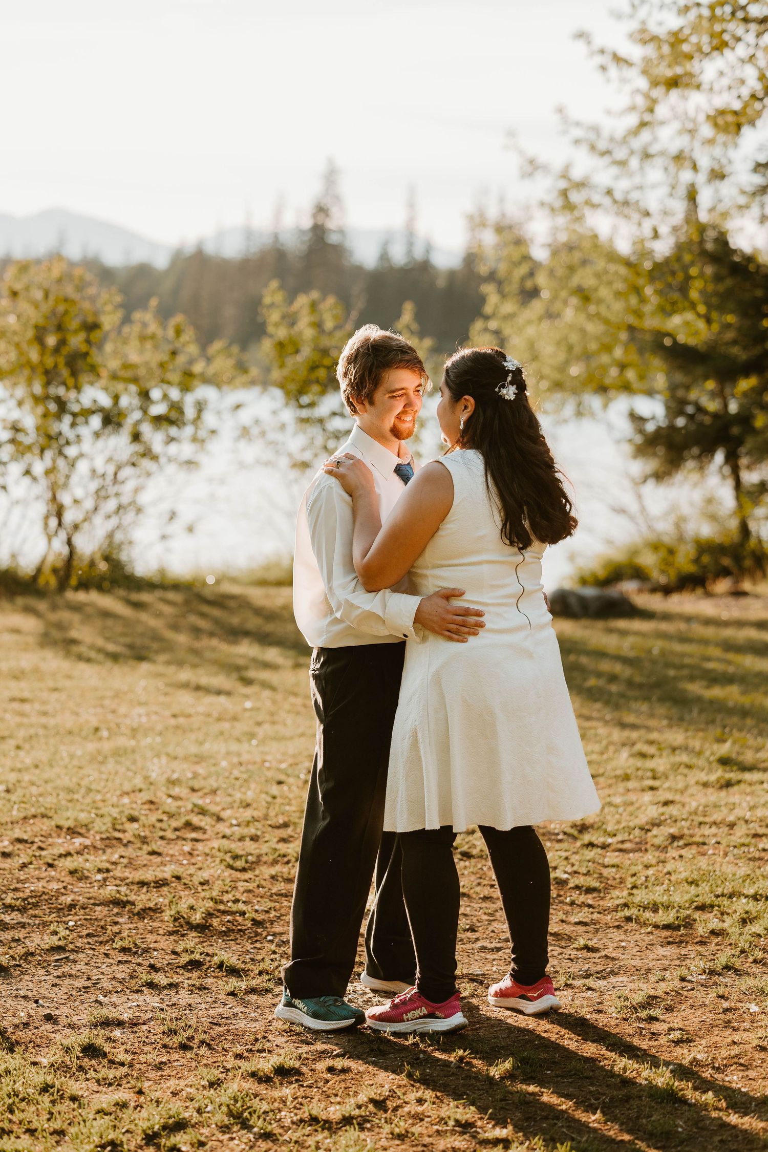 A couple dancing together in golden sunlight with mountains and trees in the background.