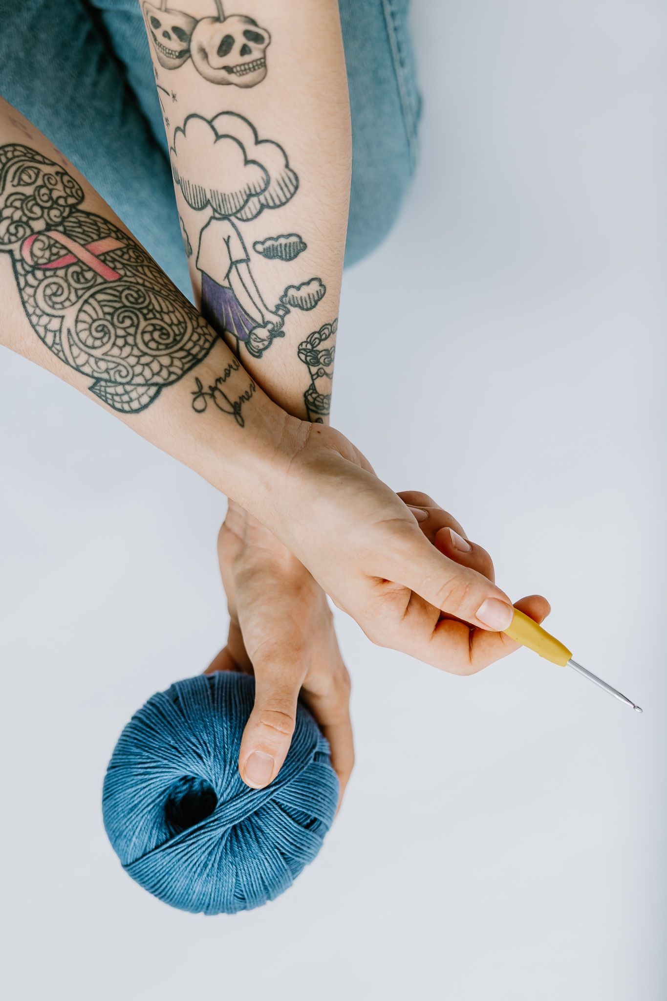 A tattooed hand holding a crochet hook works with a ball of turquoise blue yarn in a step-by-step sequence.