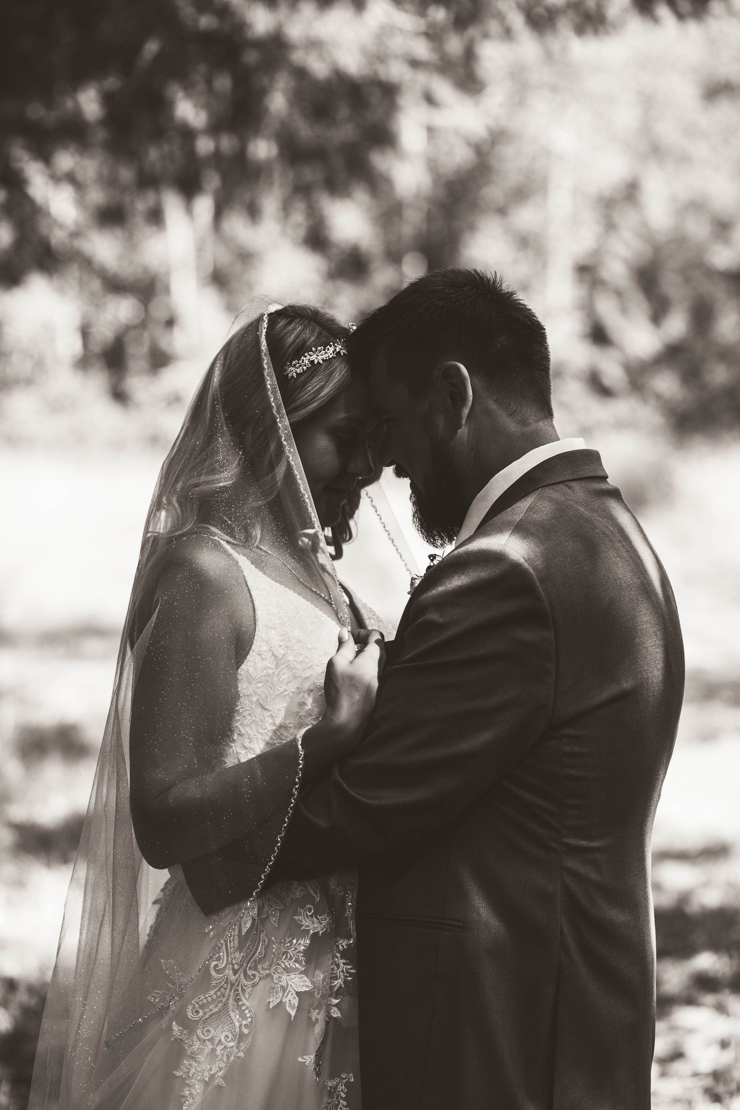 A black and white photo of a bride and groom sharing an intimate moment in a garden setting.