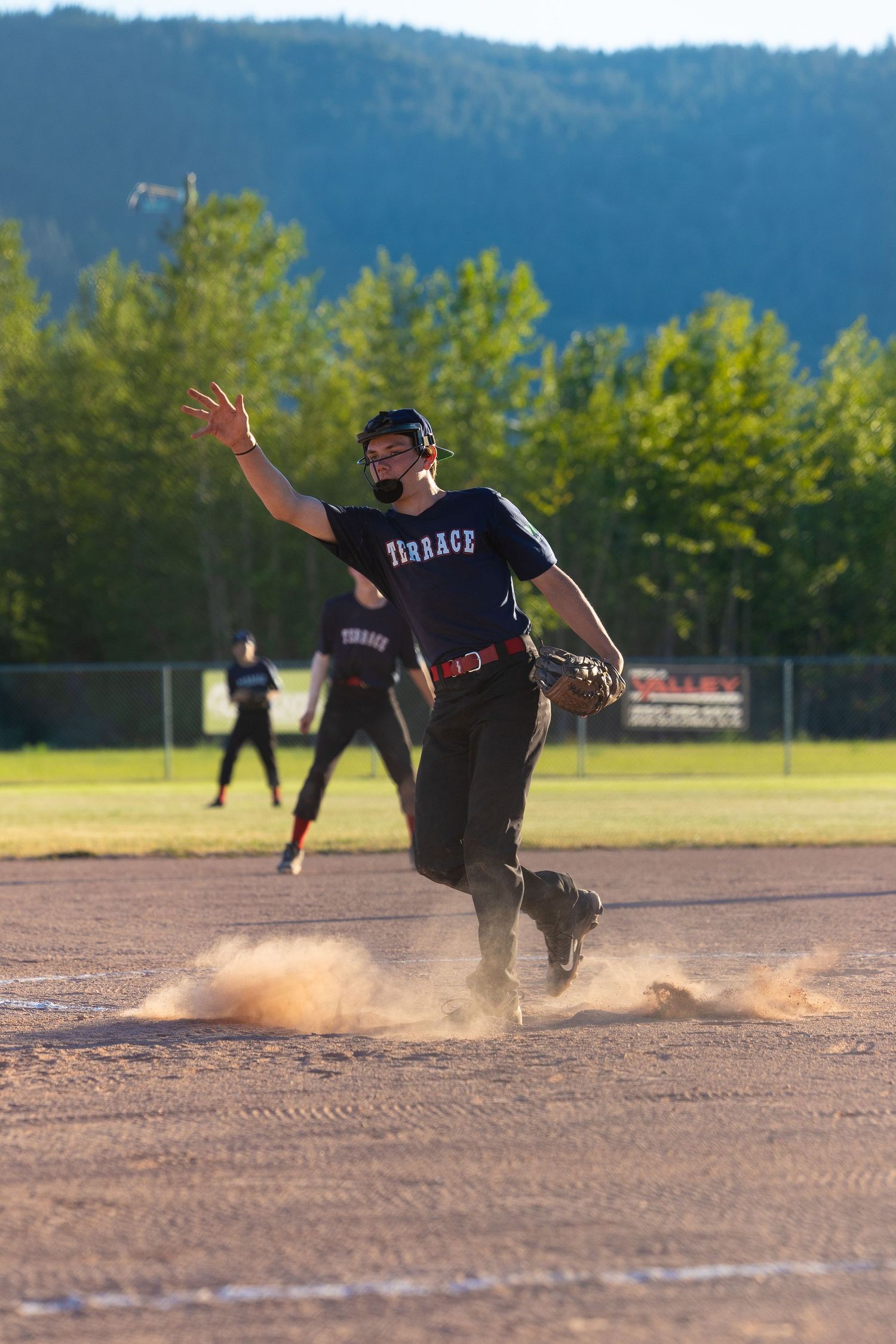 Baseball player kicks up dust while running on the baseball diamond during a game.