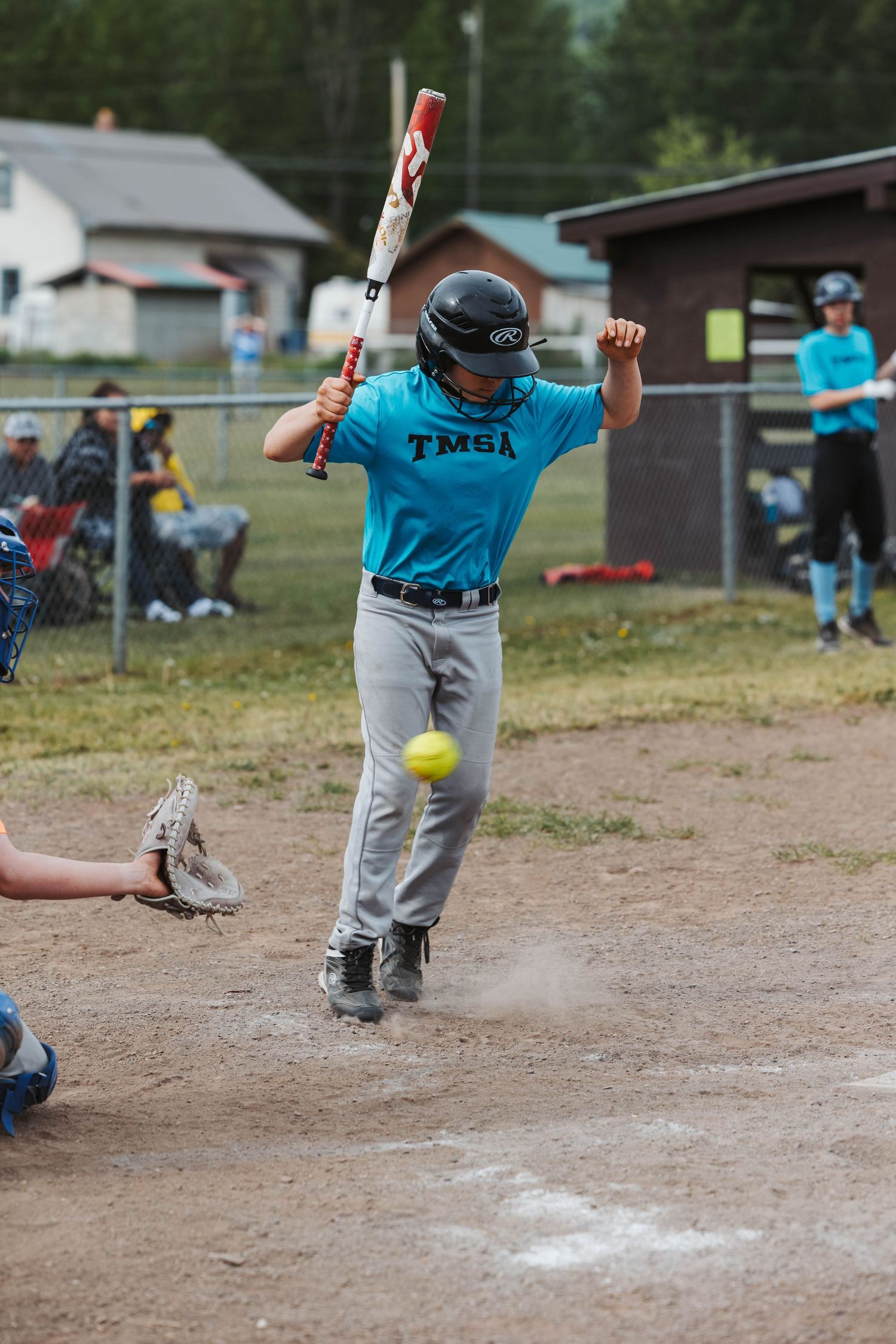 Youth baseball player in teal TMSA jersey swings at pitch during game.