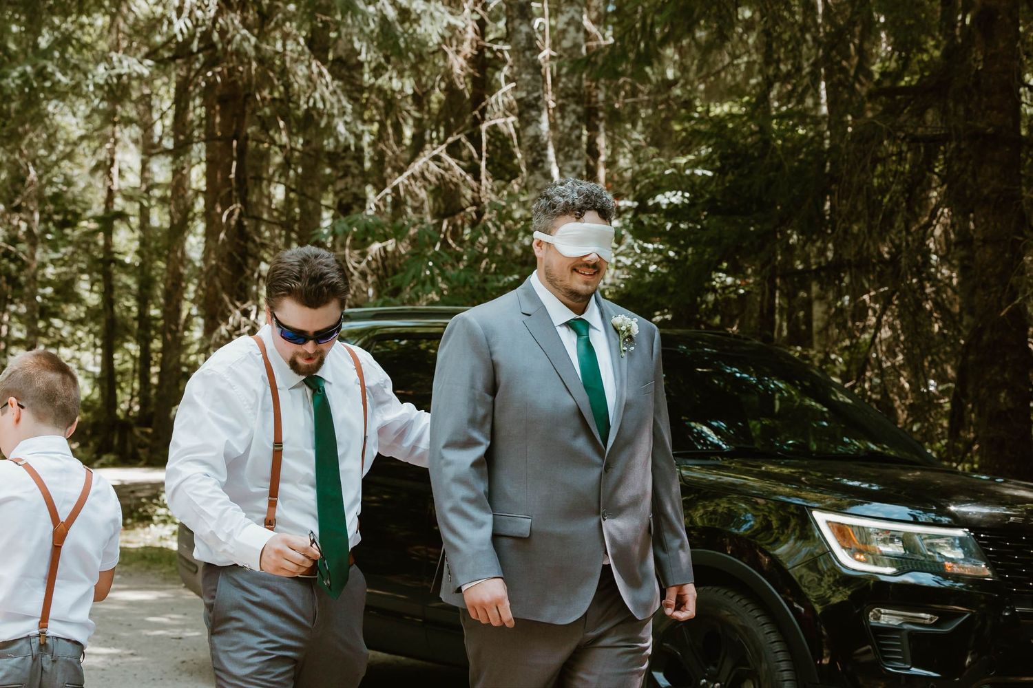 Wedding party members in teal ties and grey suits arrive at outdoor venue.
