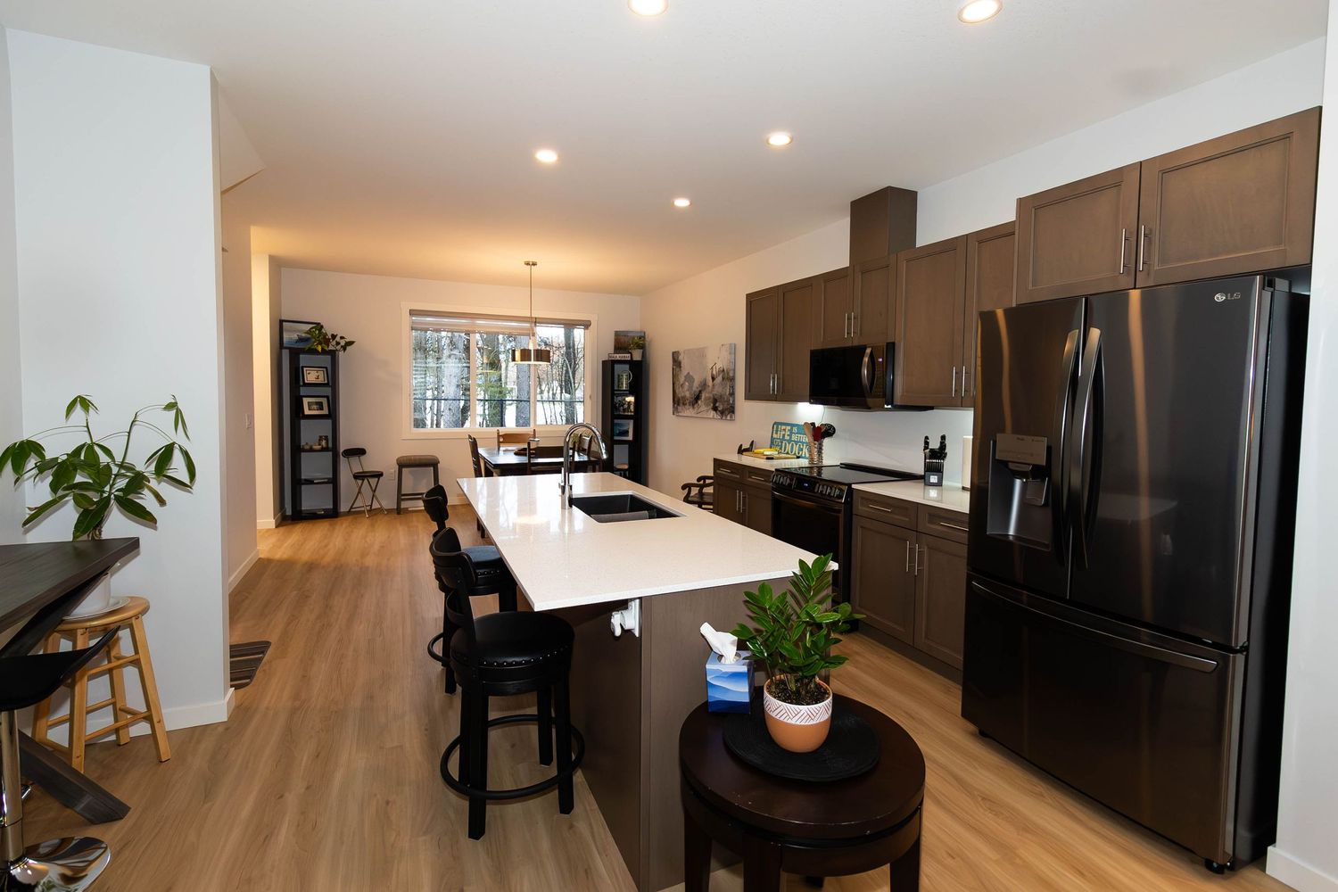 Modern kitchen with dark cabinets, stainless appliances and white island with bar seating.