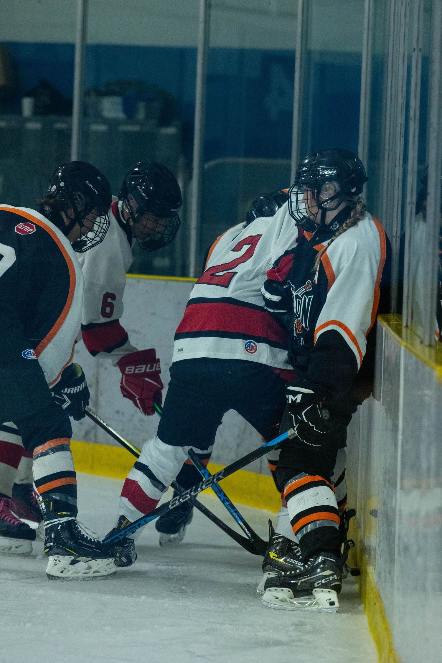 Ice hockey players battle for the puck along the boards during an intense game.