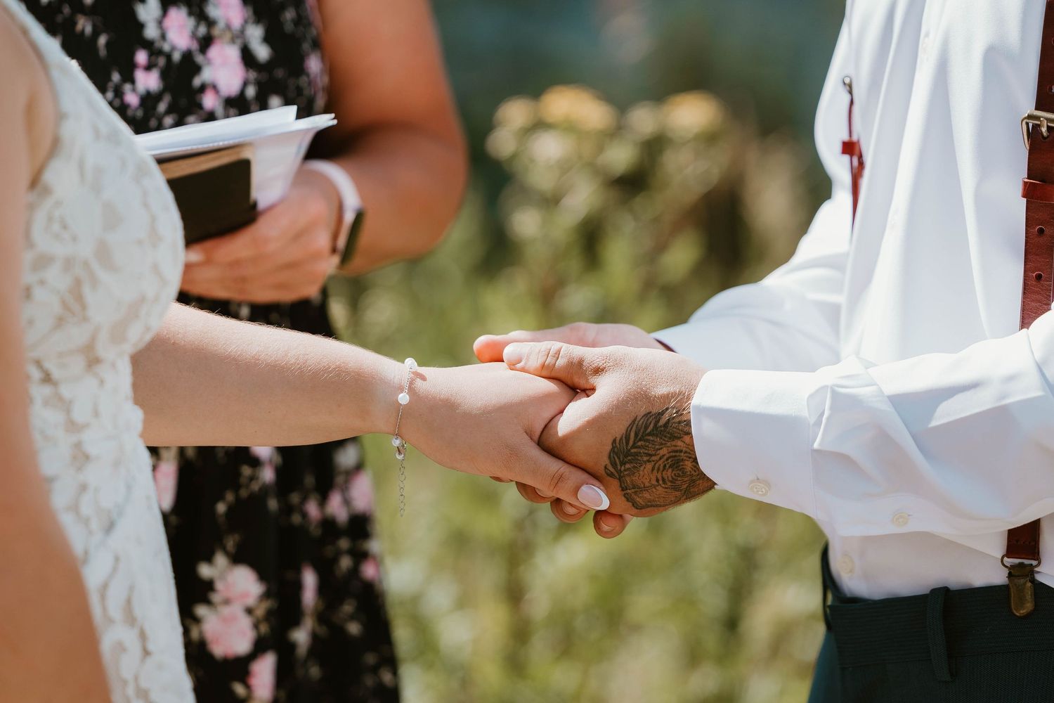 Close-up of hands exchanging rings during a mountain wedding ceremony.