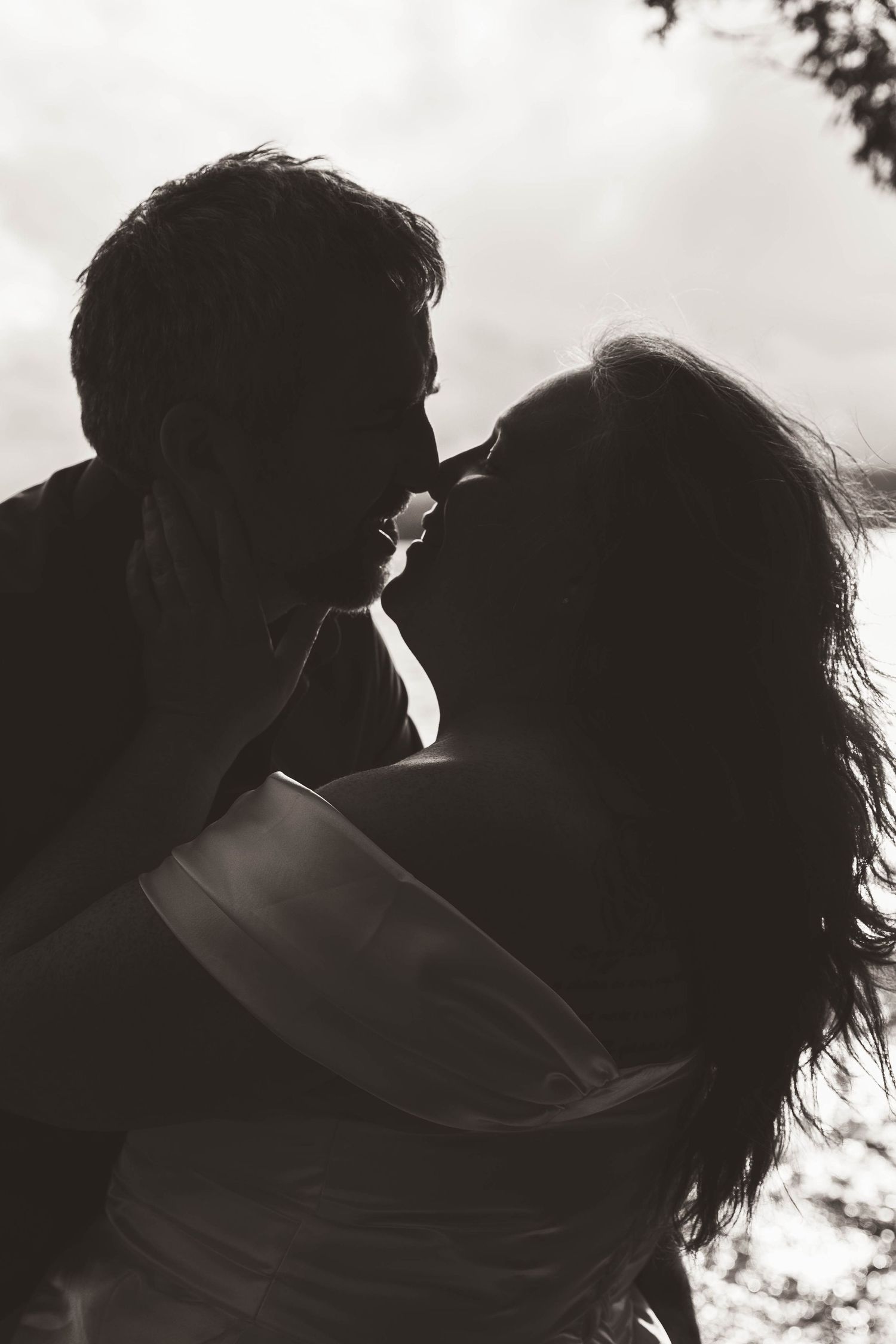 Intimate black and white silhouette of a couple in a tender embrace outdoors.
