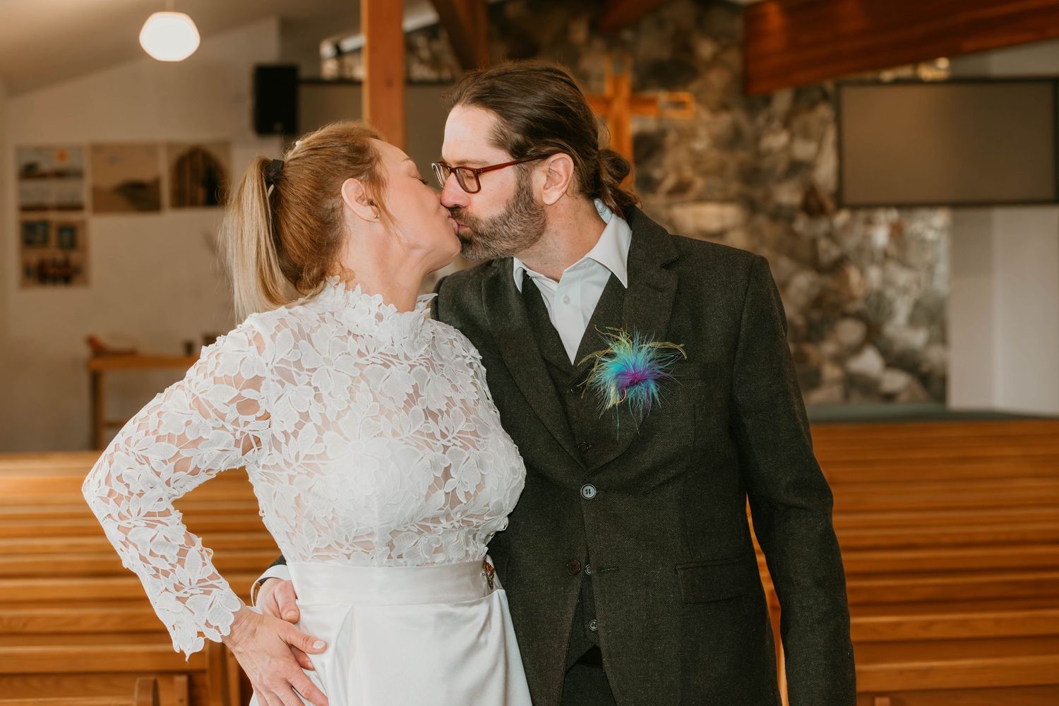 A romantic moment between newlyweds in a church with wooden pews and stone walls.