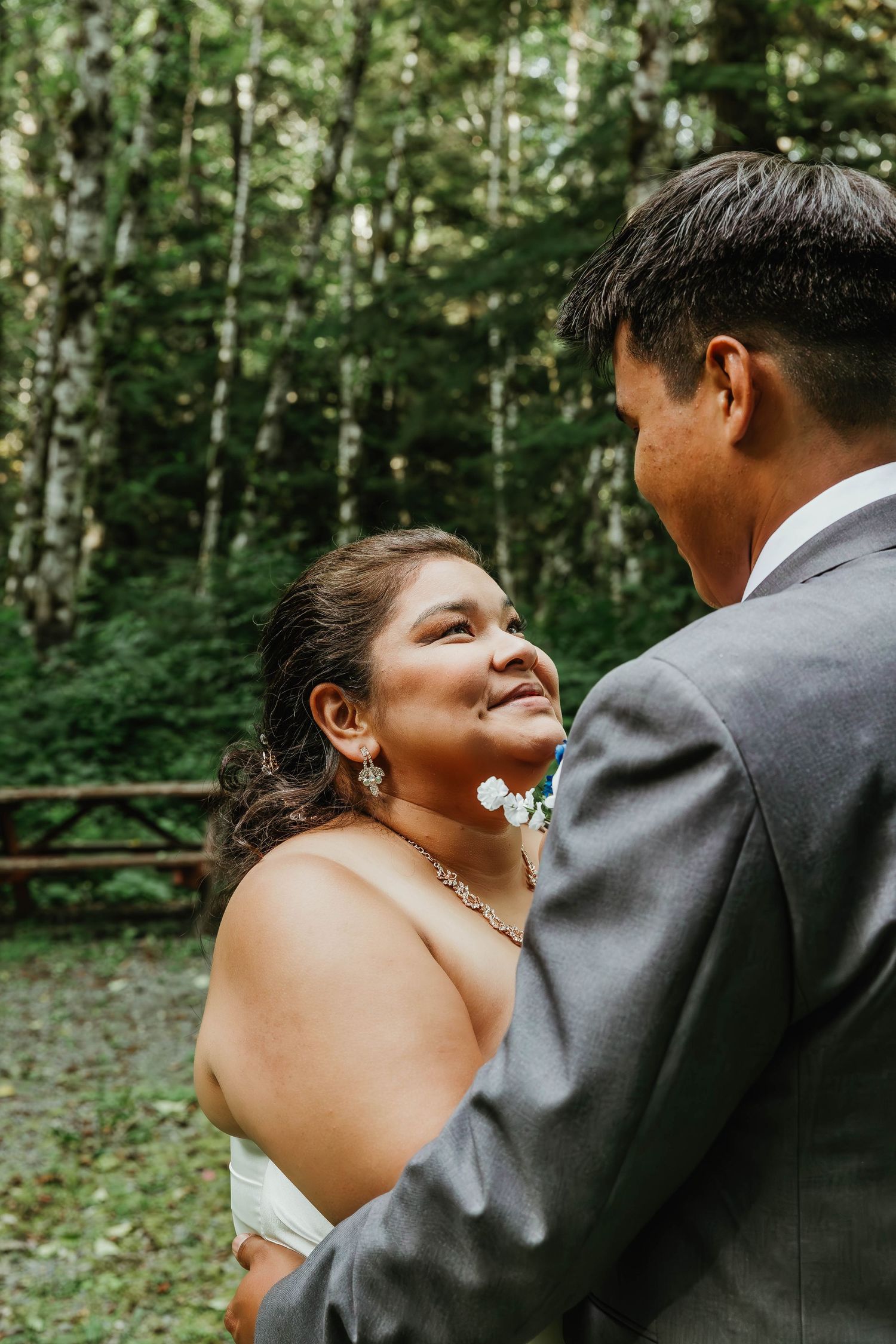 A romantic moment between newlyweds in a forest setting.