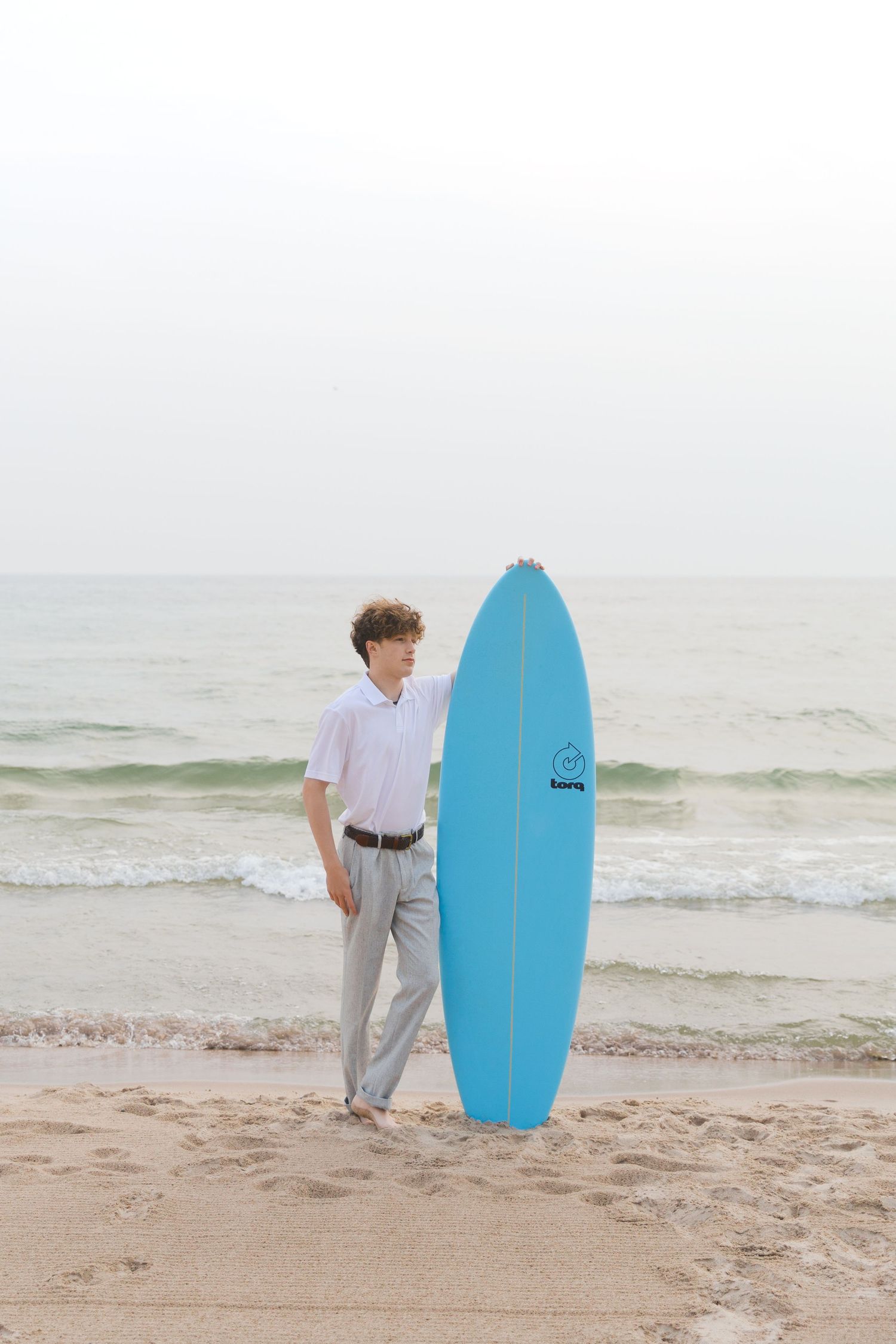 Grand Haven Lake Michigan Beach Senior Portrait Photoshoot. Sand dunes, beach grass, and the great lakes on the boardwalk with a surfboard