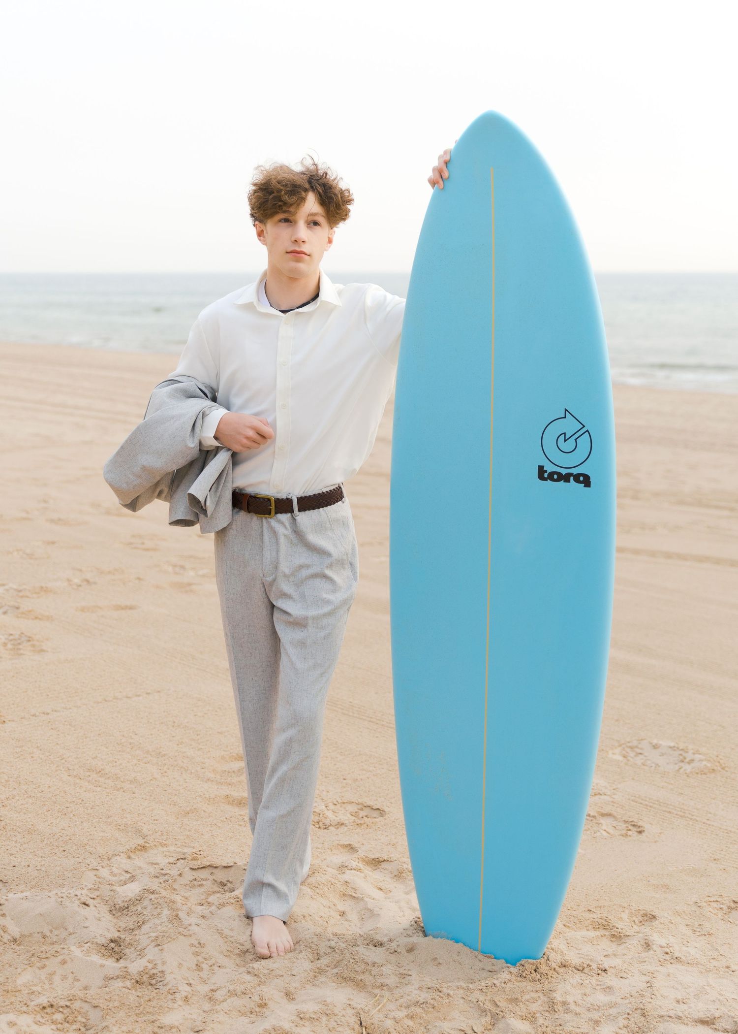 Grand Haven Lake Michigan Beach Senior Portrait Photoshoot. Sand dunes, beach grass, and the great lakes on the boardwalk with a surfboard
