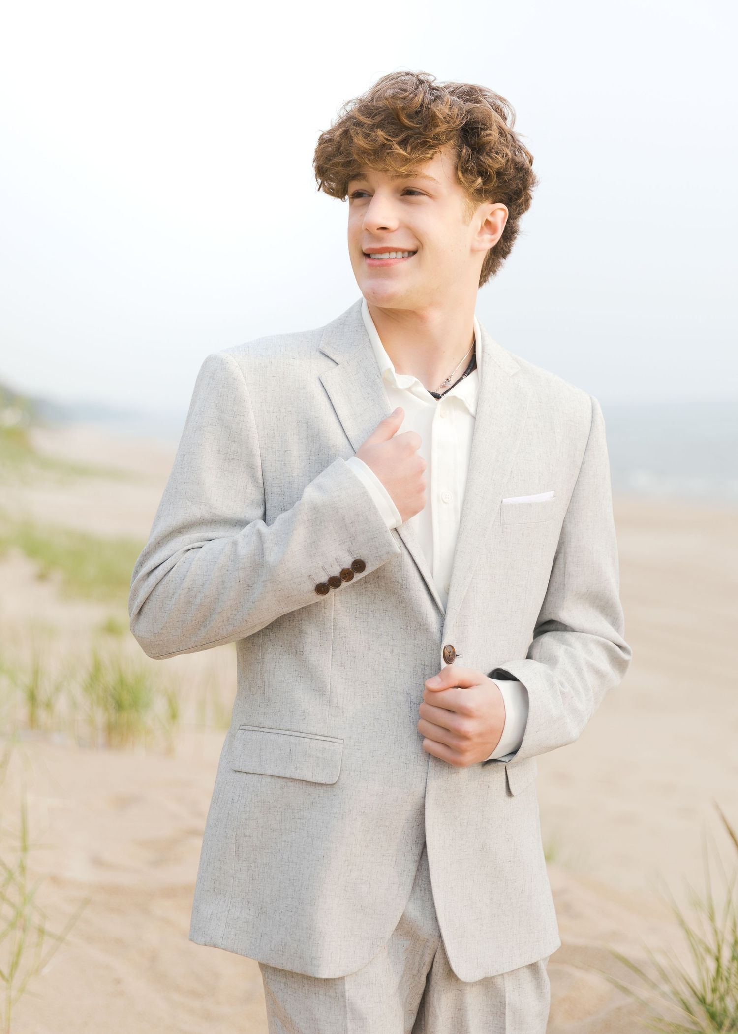 Grand Haven Lake Michigan Beach Senior Portrait Photoshoot. Sand dunes, beach grass, and the great lakes on the boardwalk with a surfboard